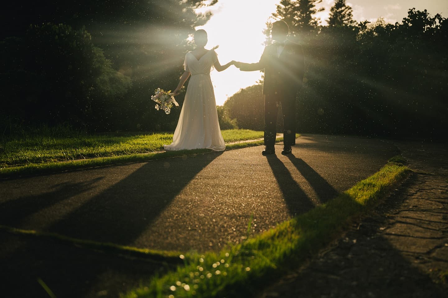Sunset rays light a tree-lined Okinawa road as a couple joins hands
