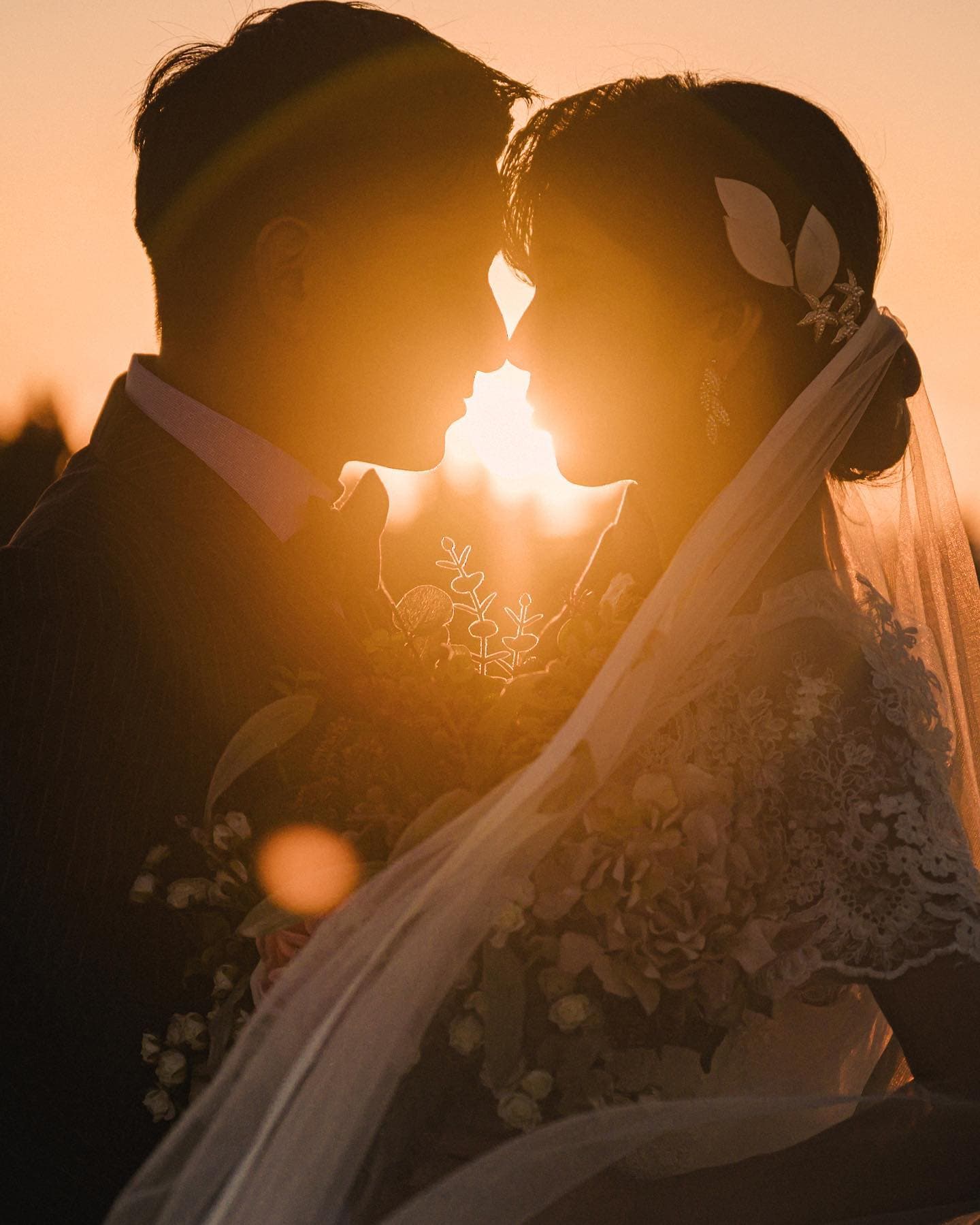 Bride and groom nose to nose with the setting sun blazing between them in Okinawa