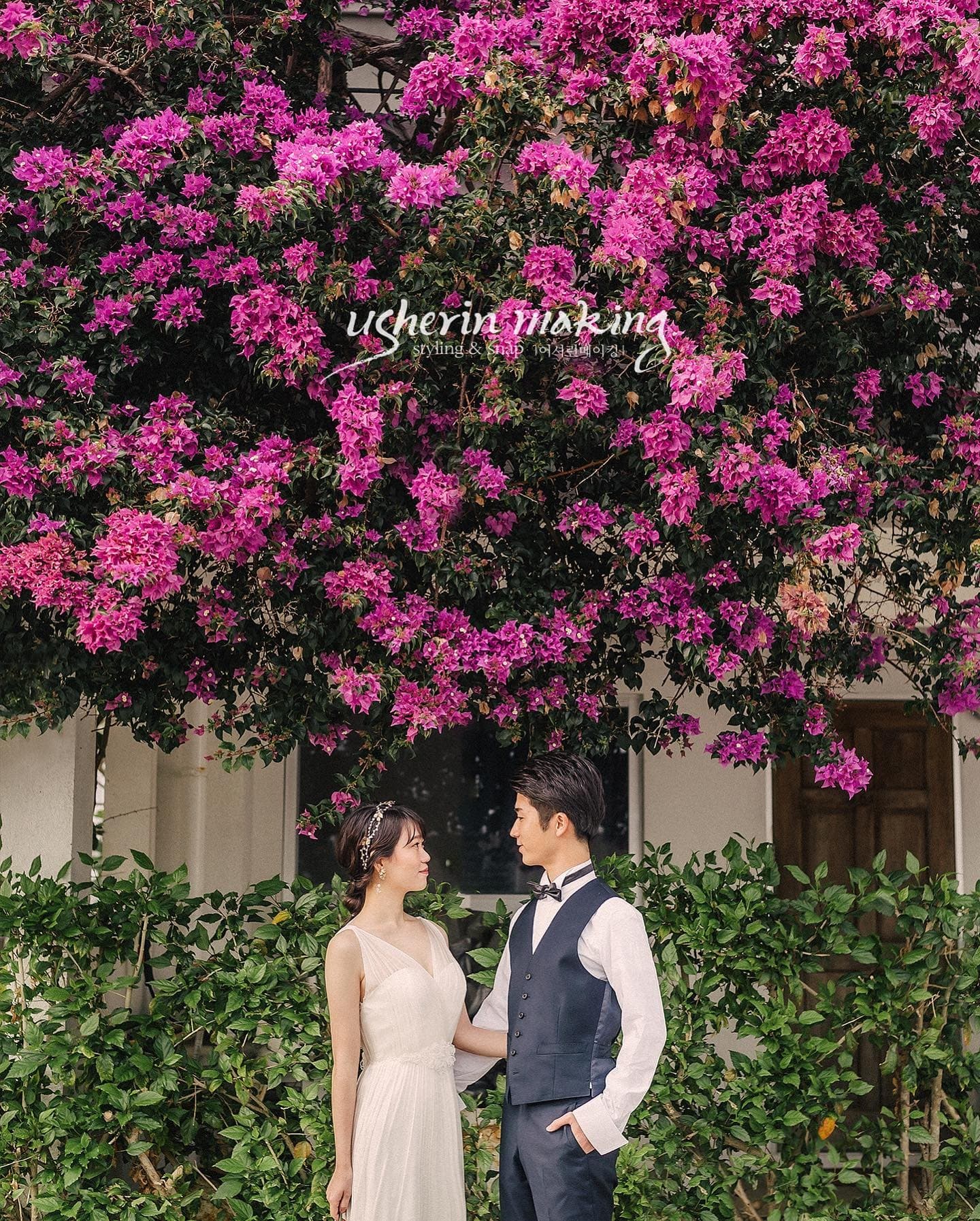 Couple gazing at each other beneath a wall of vivid pink bougainvillea in Okinawa.