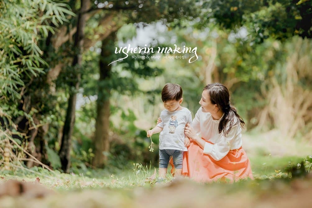 沖縄の森の草むらで幼い息子と草花を摘む母親