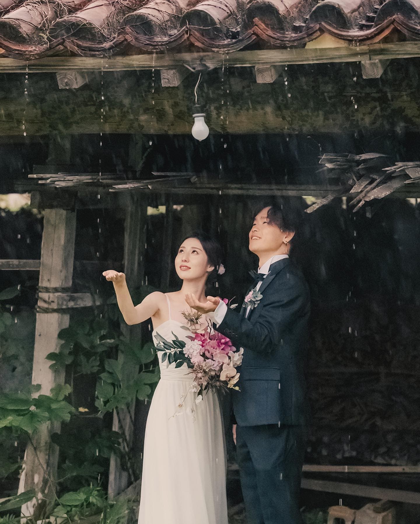 오키나와 붉은 기와 처마 밑에서 빗방울을 바라보는 신랑신부