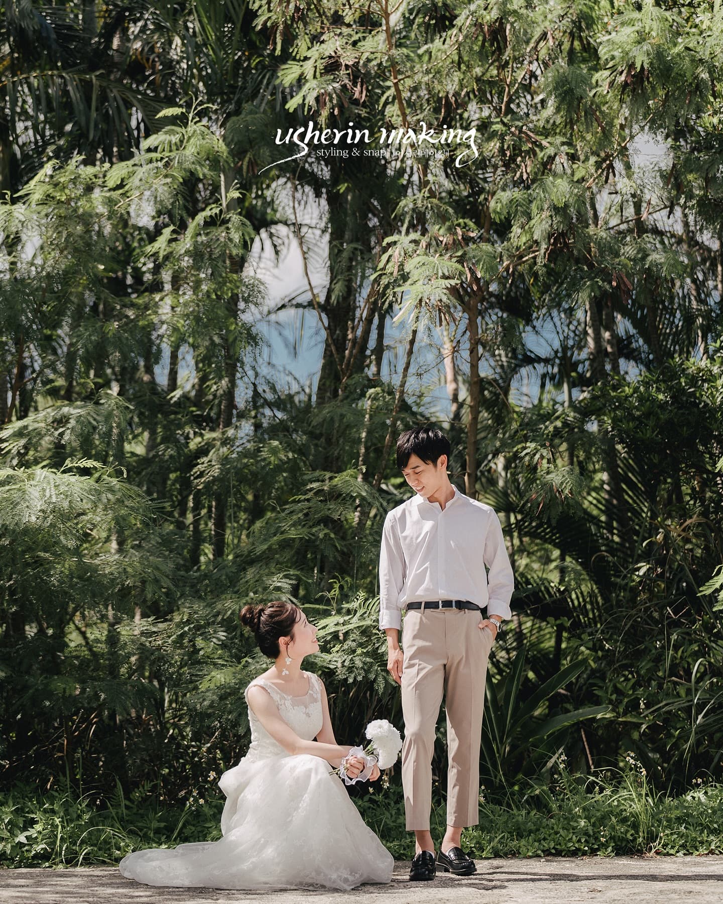 Bride seated in her gown and groom standing among Okinawa's lush winter greenery