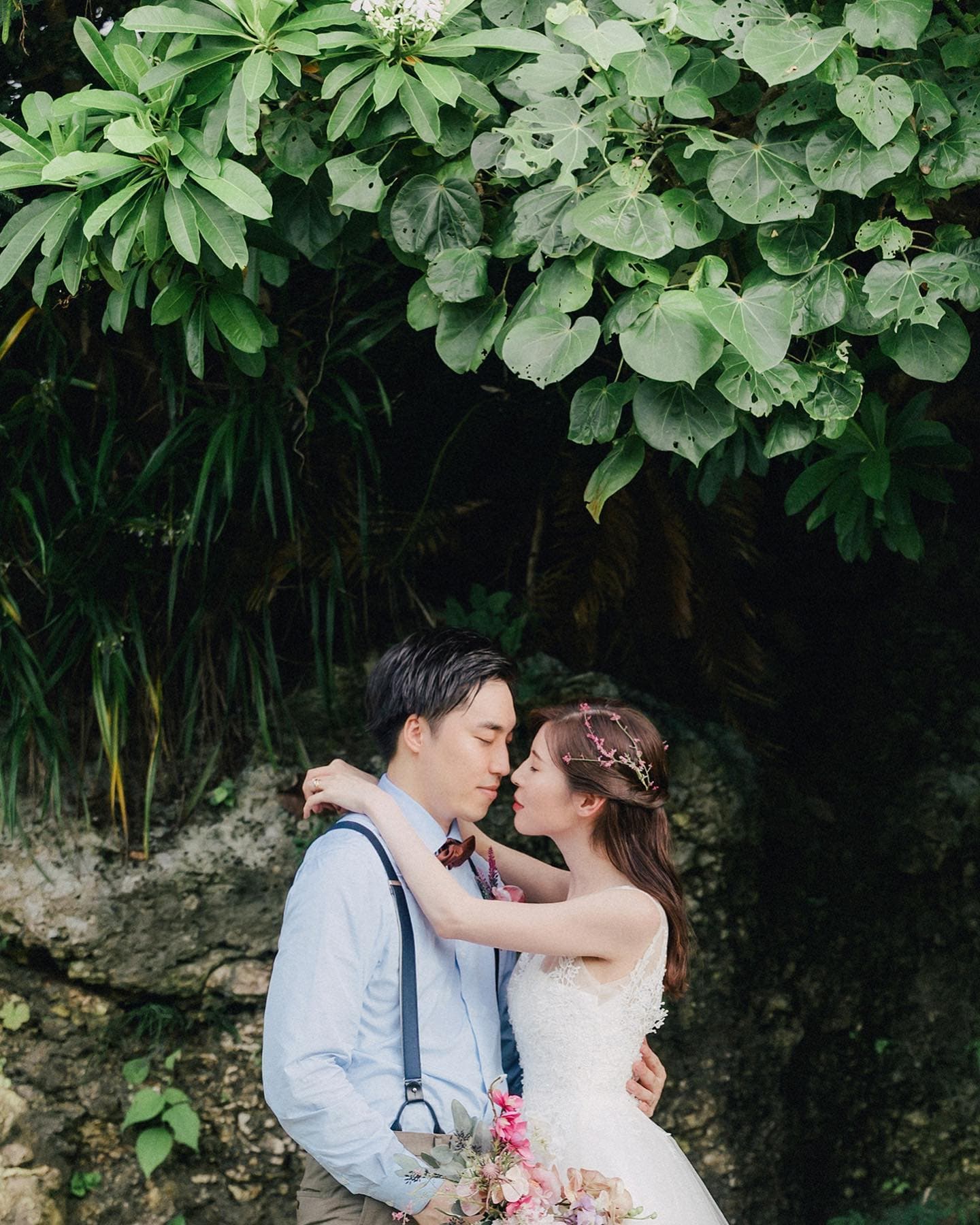 大きな緑の葉の下でキスを交わす新郎新婦、沖縄