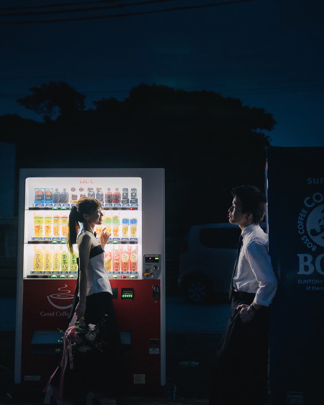 Couple facing each other by a vending machine on a night street