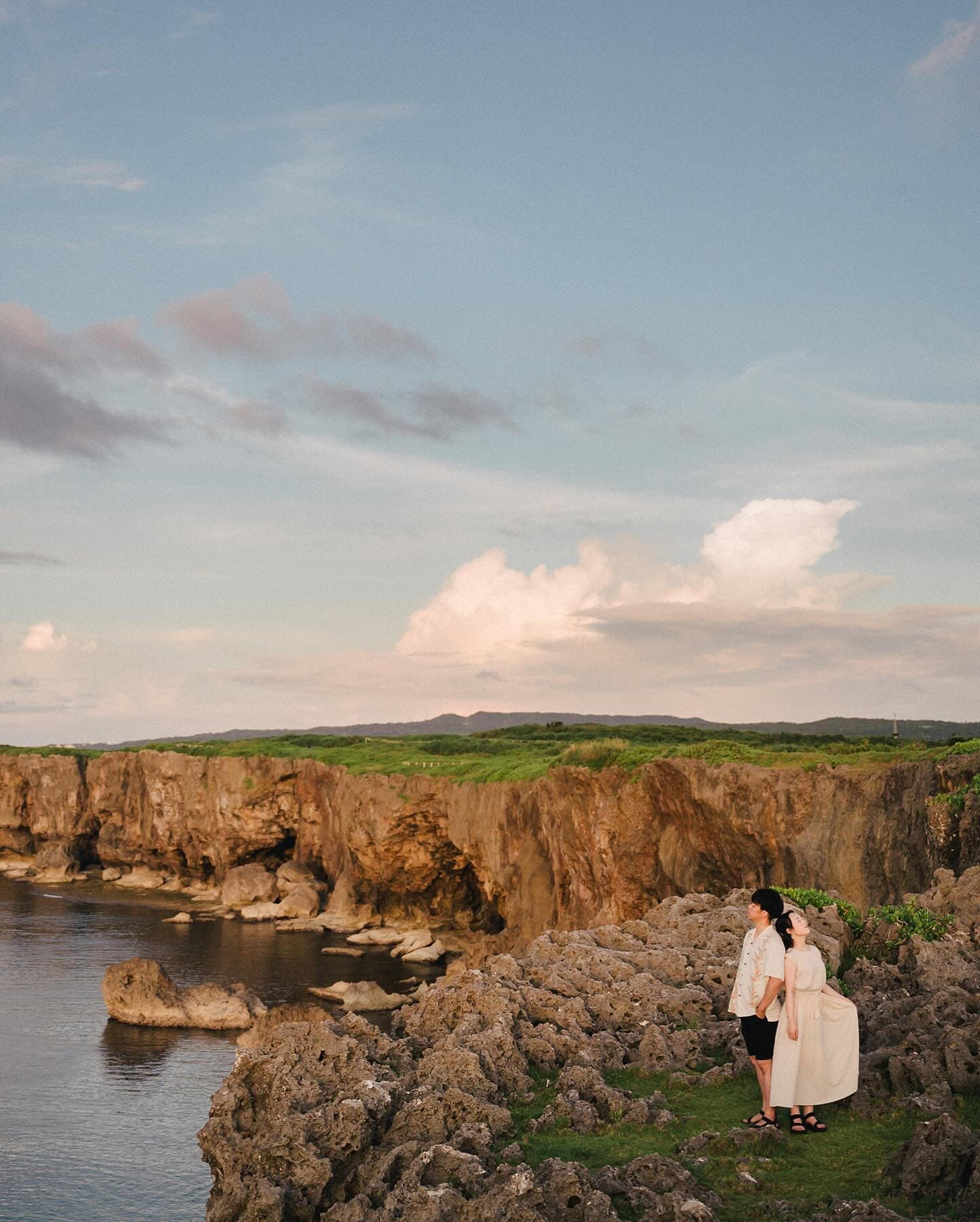 Couple on a rugged sea cliff overlooking the ocean under a blue Okinawa sky