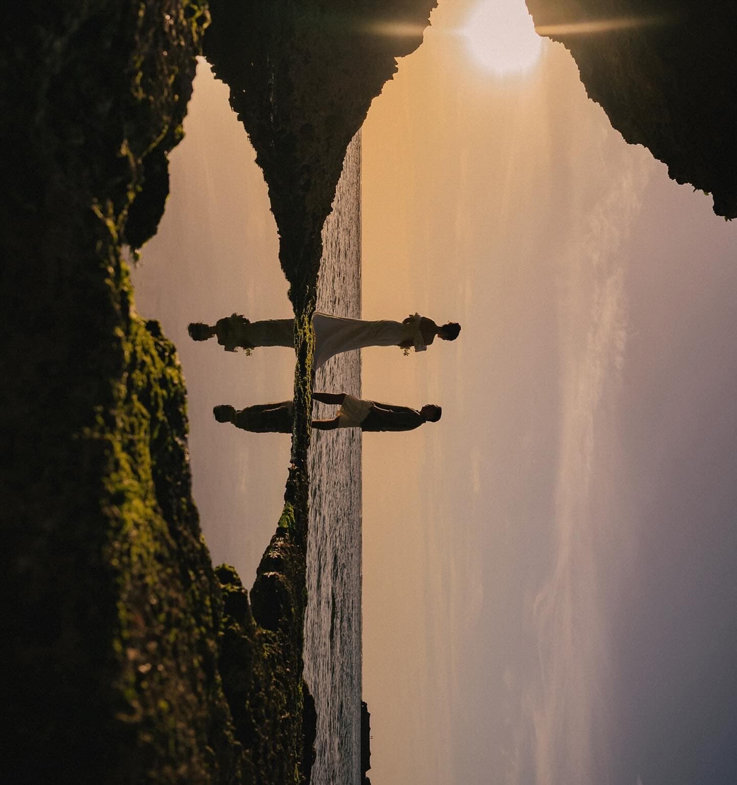 A couple stands among coastal rocks at sunset in Okinawa