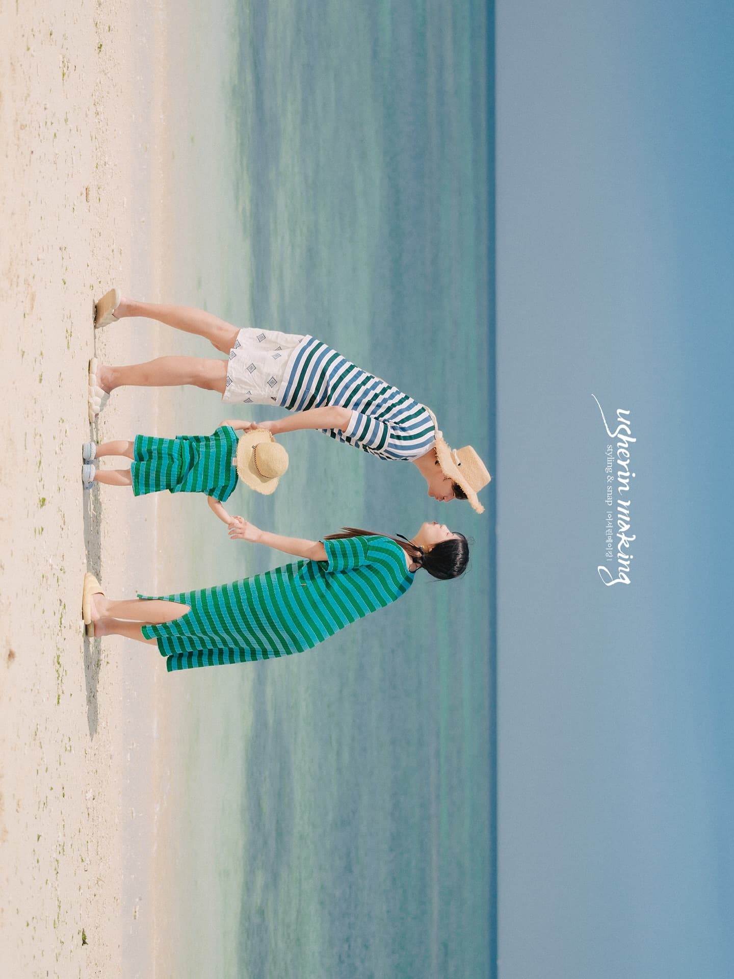 Family of three in matching stripes walking a white Miyakojima beach