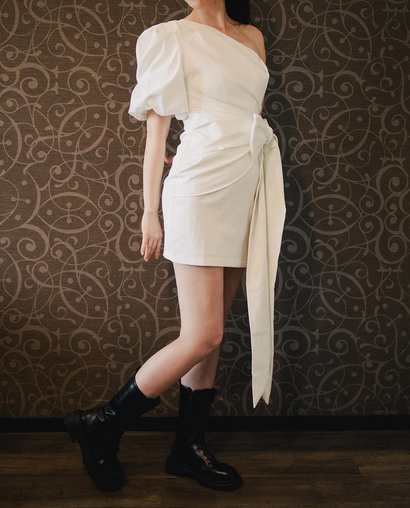 Side view of a one-shoulder mini dress styled with black combat boots