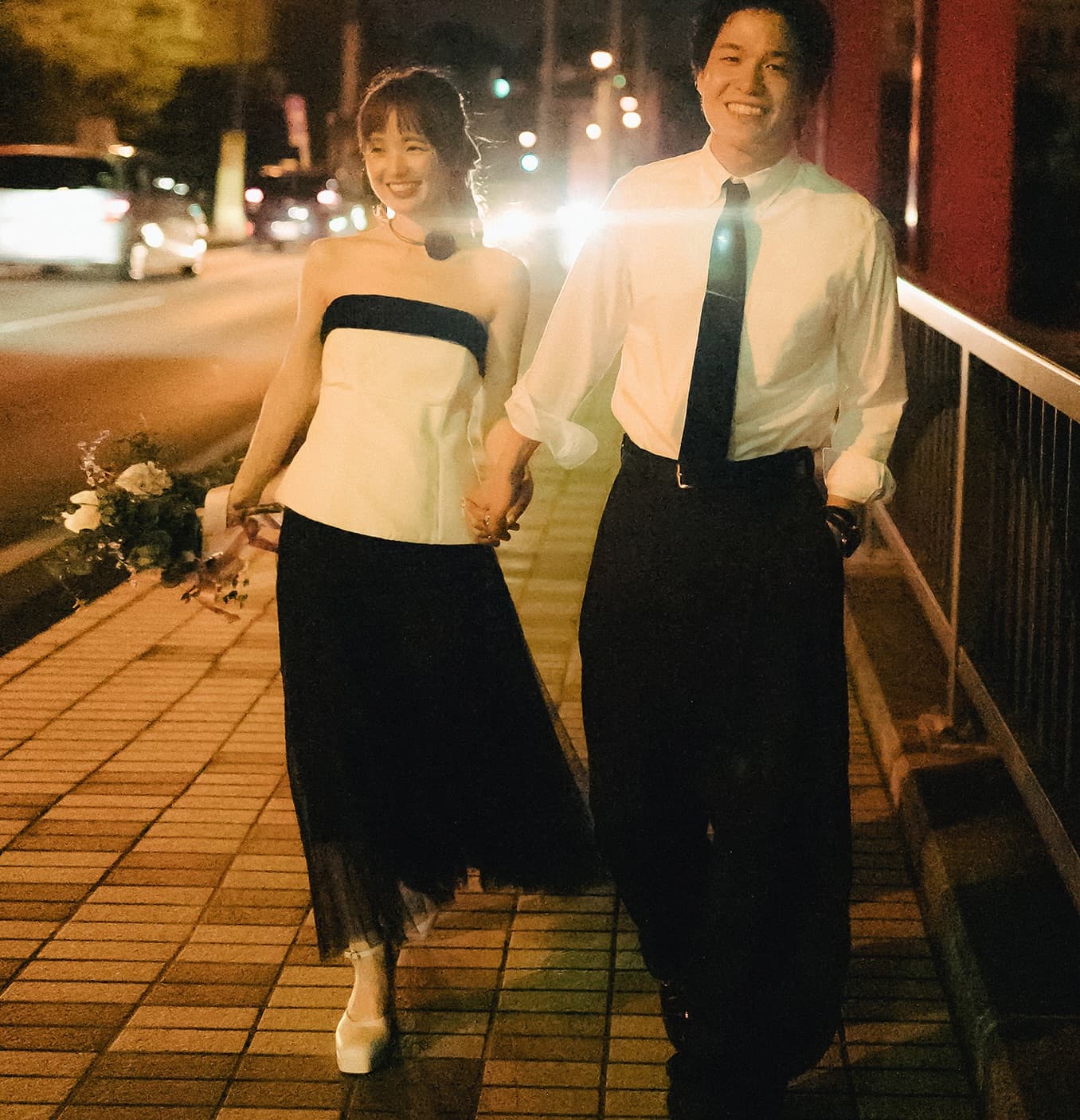 Couple walking a city street at night, white strapless top styled with a long black tulle skirt