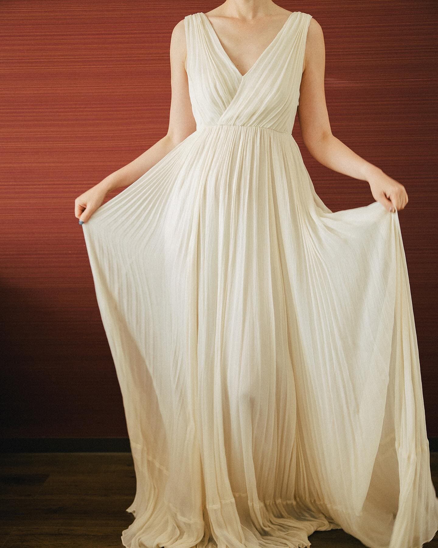 Ivory pleated chiffon gown with a sleeveless V-neck, full length from the front