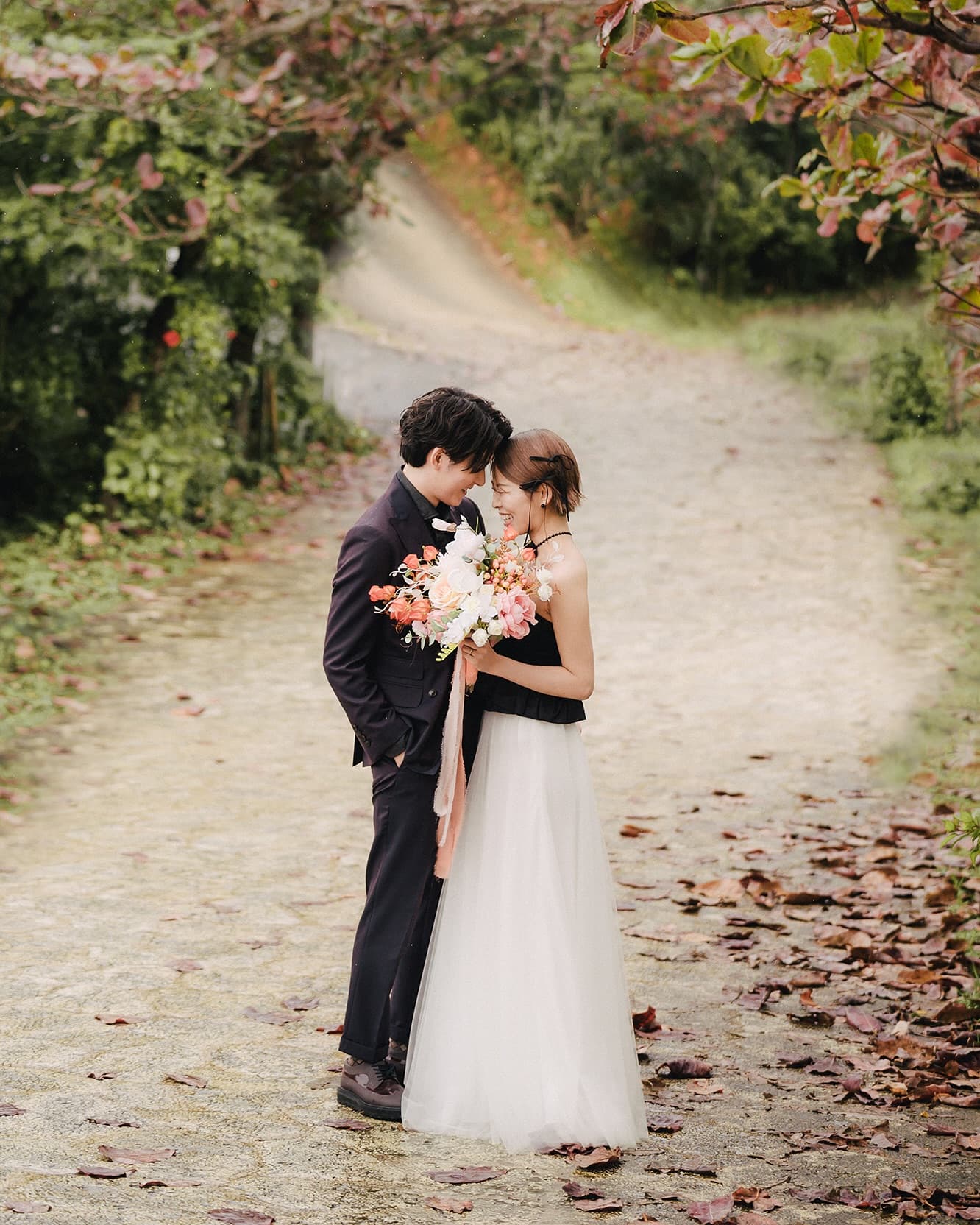 Black halter top paired with a white tulle skirt on a leafy path, bouquet in hand