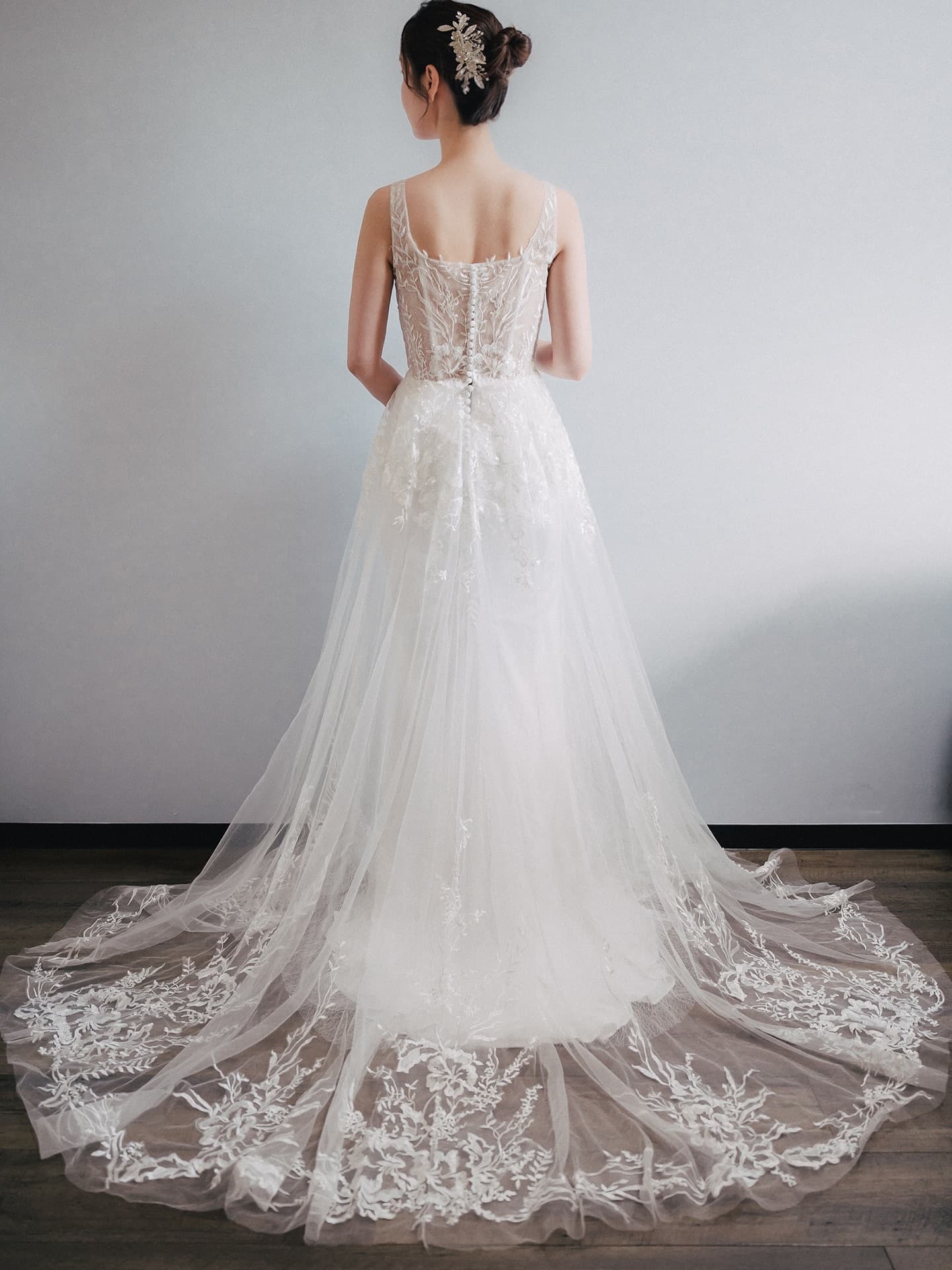 Back view of the tulle gown with a long floral-embroidered train spread on the floor