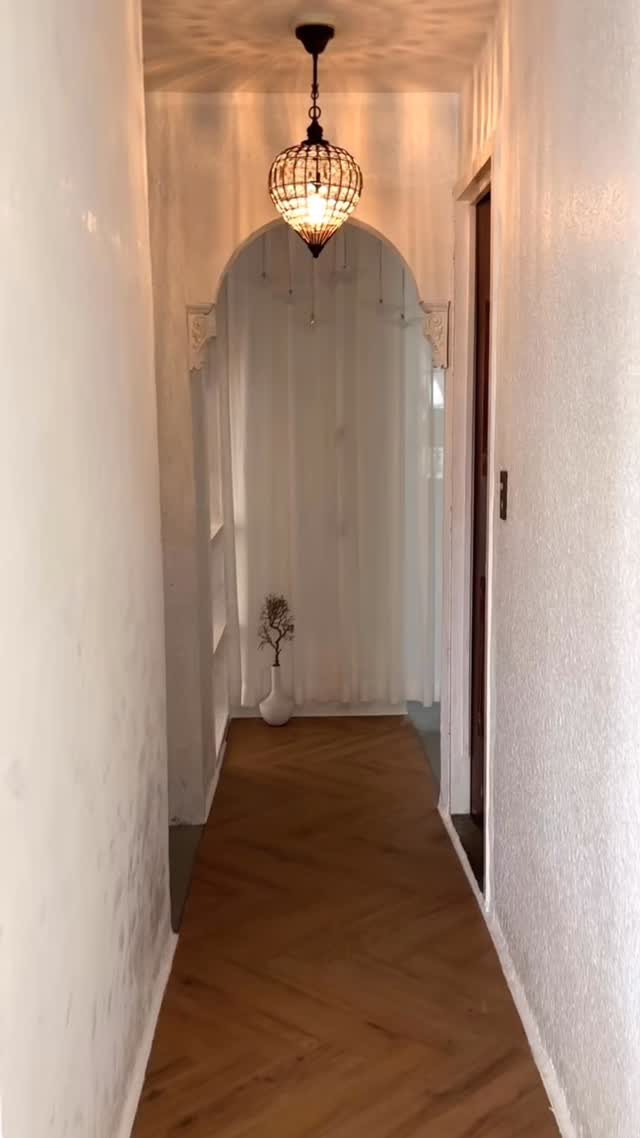 Inside the dress shop, an arched fitting area lit by a small chandelier
