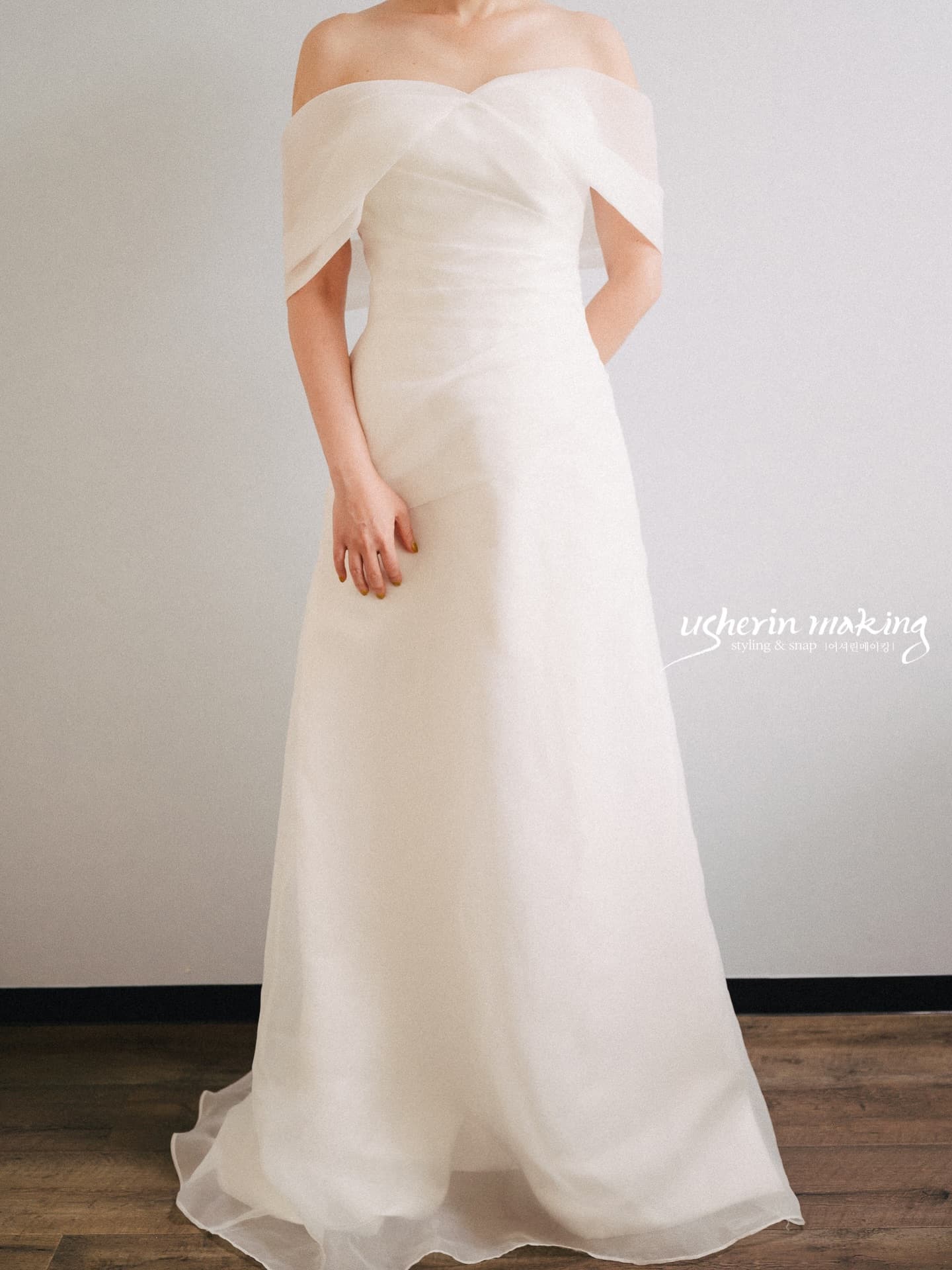 Front view of an off-shoulder organza gown with a sheer A-line skirt
