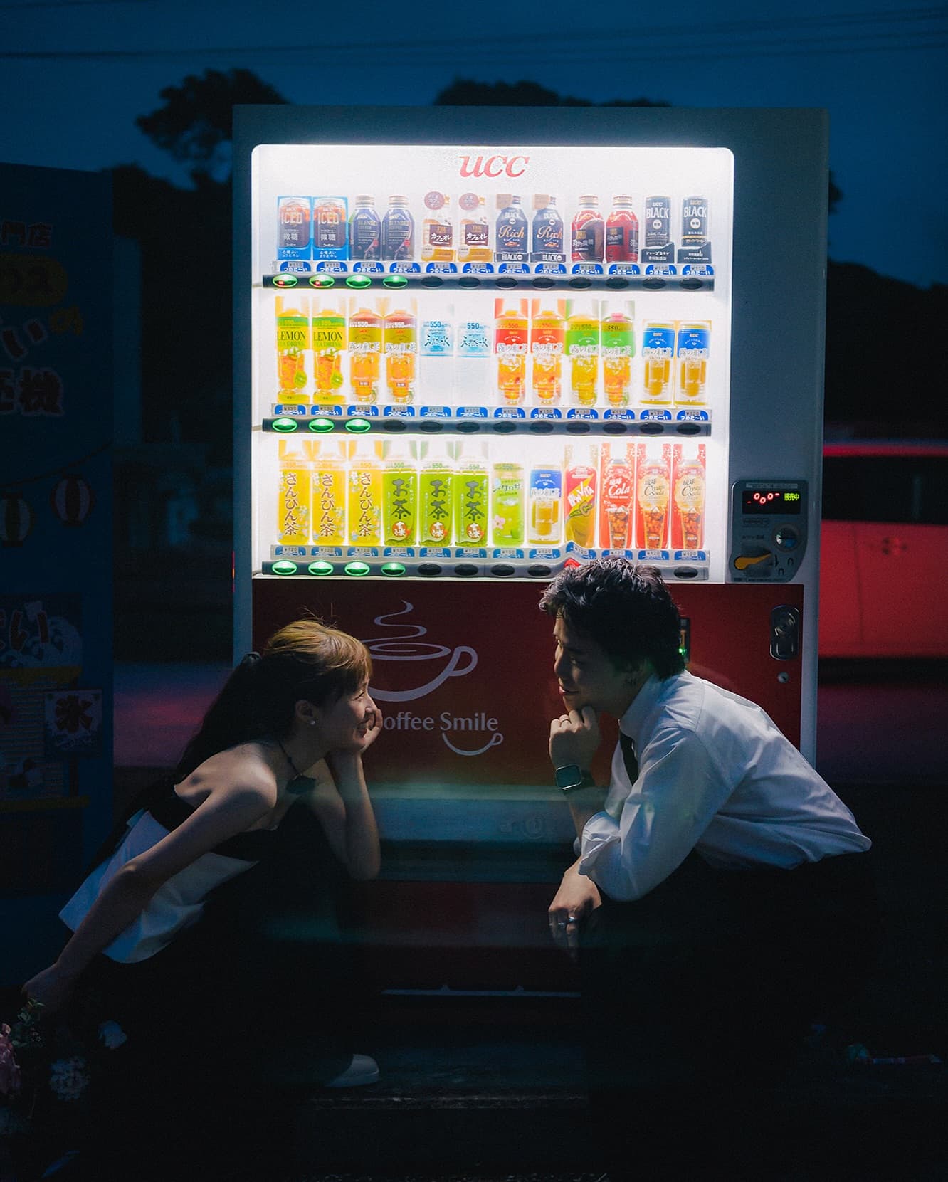 Couple face to face by a glowing vending machine at night in Okinawa
