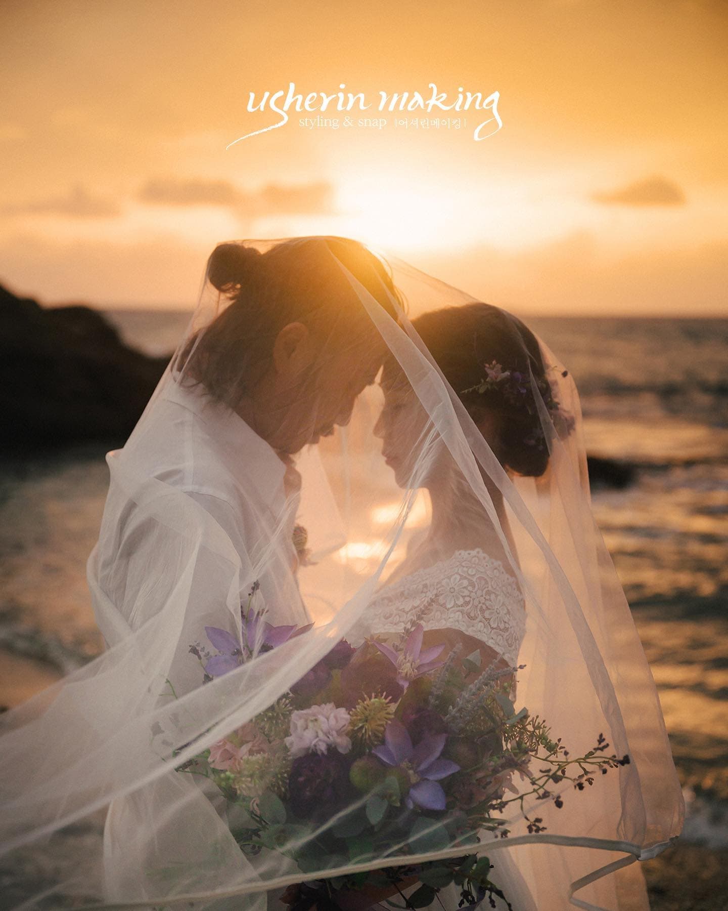Couple wrapped in a sheer veil against a golden sunset over the sea in Okinawa