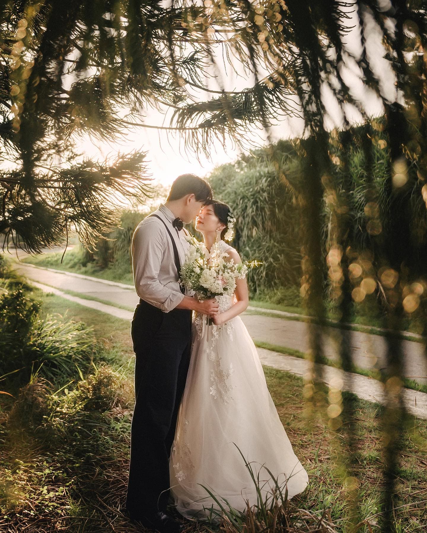 Couple gazing at each other with a white bouquet on a sunlit path