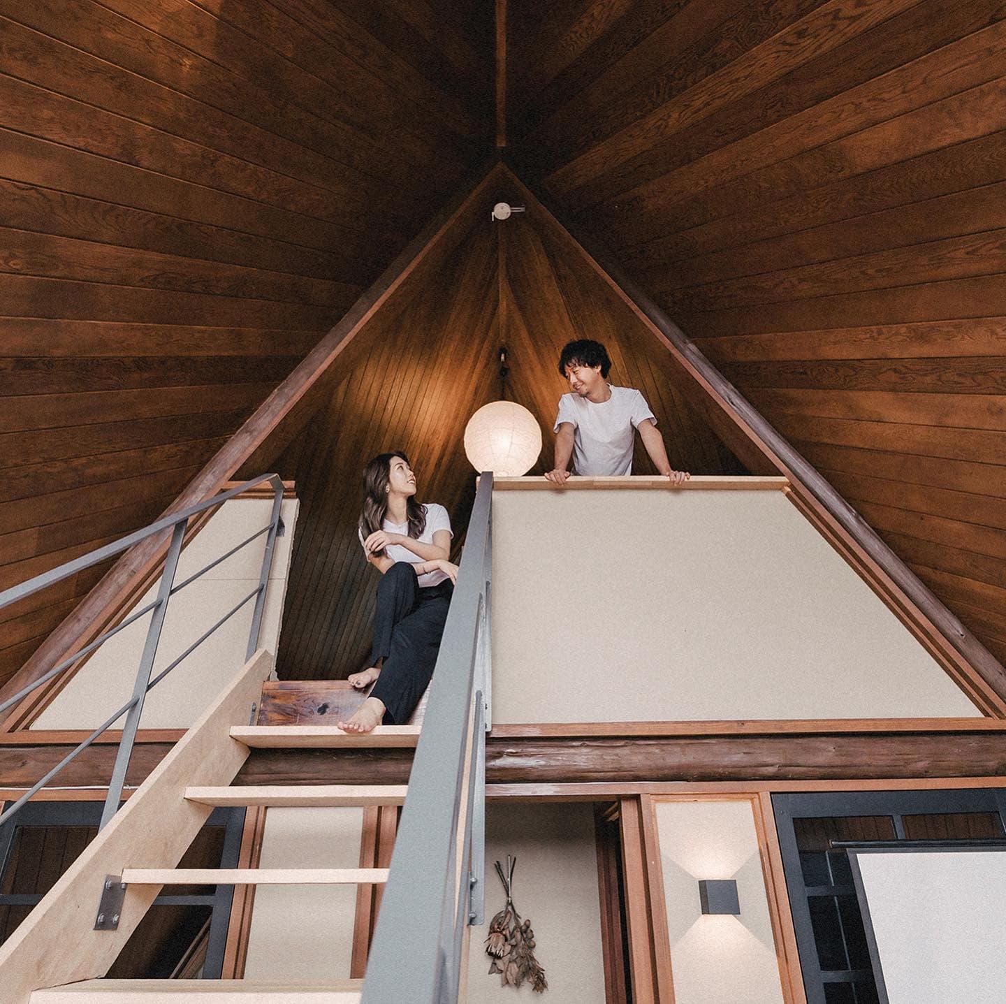 Couple exchanging glances across the staircase of an A-frame cabin interior