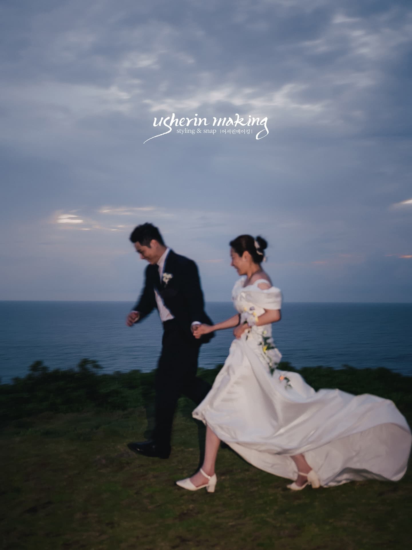 Bride and groom running hand in hand across a seaside meadow at dusk in Okinawa