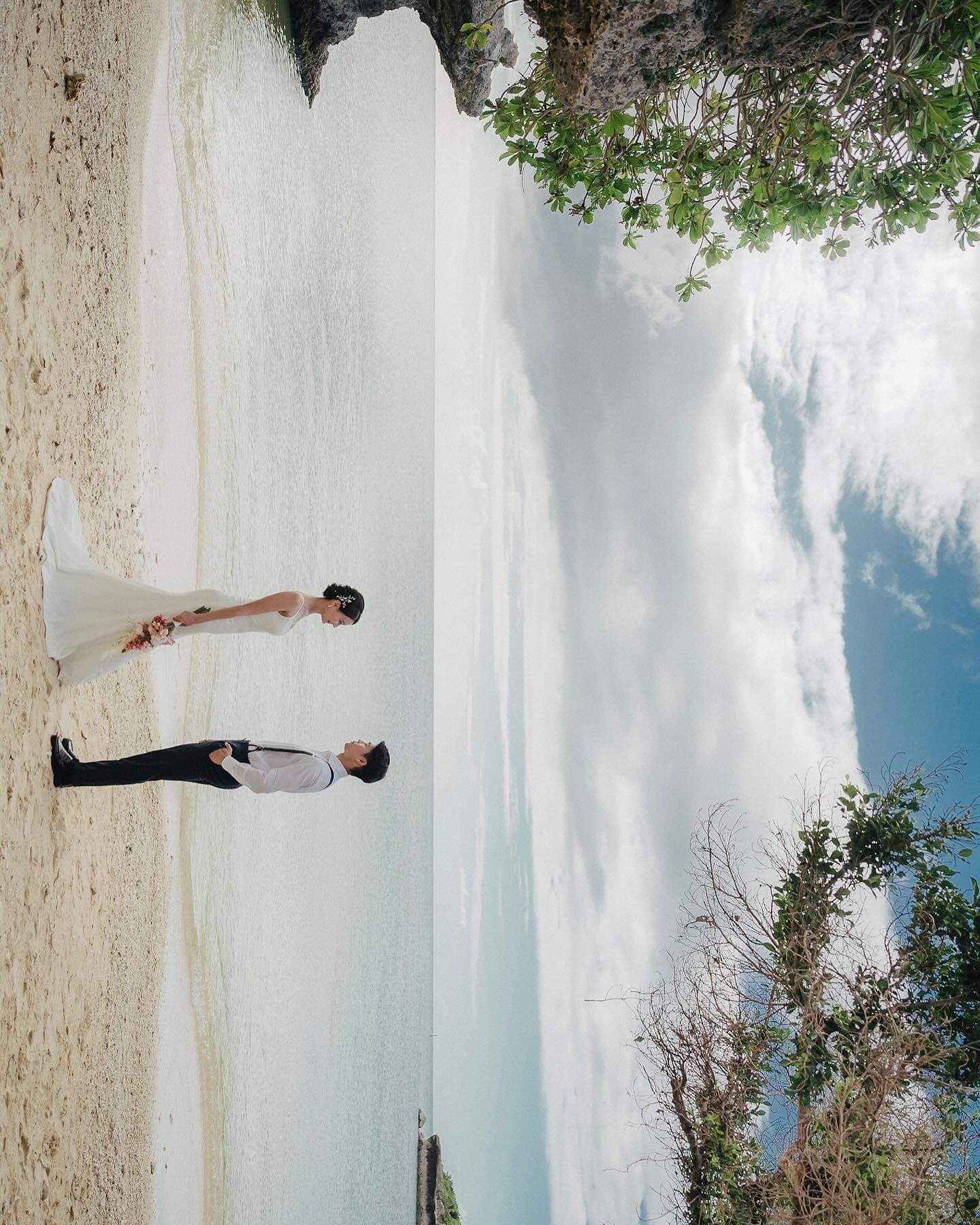 Couple facing each other on a white Okinawa beach under a blue sky