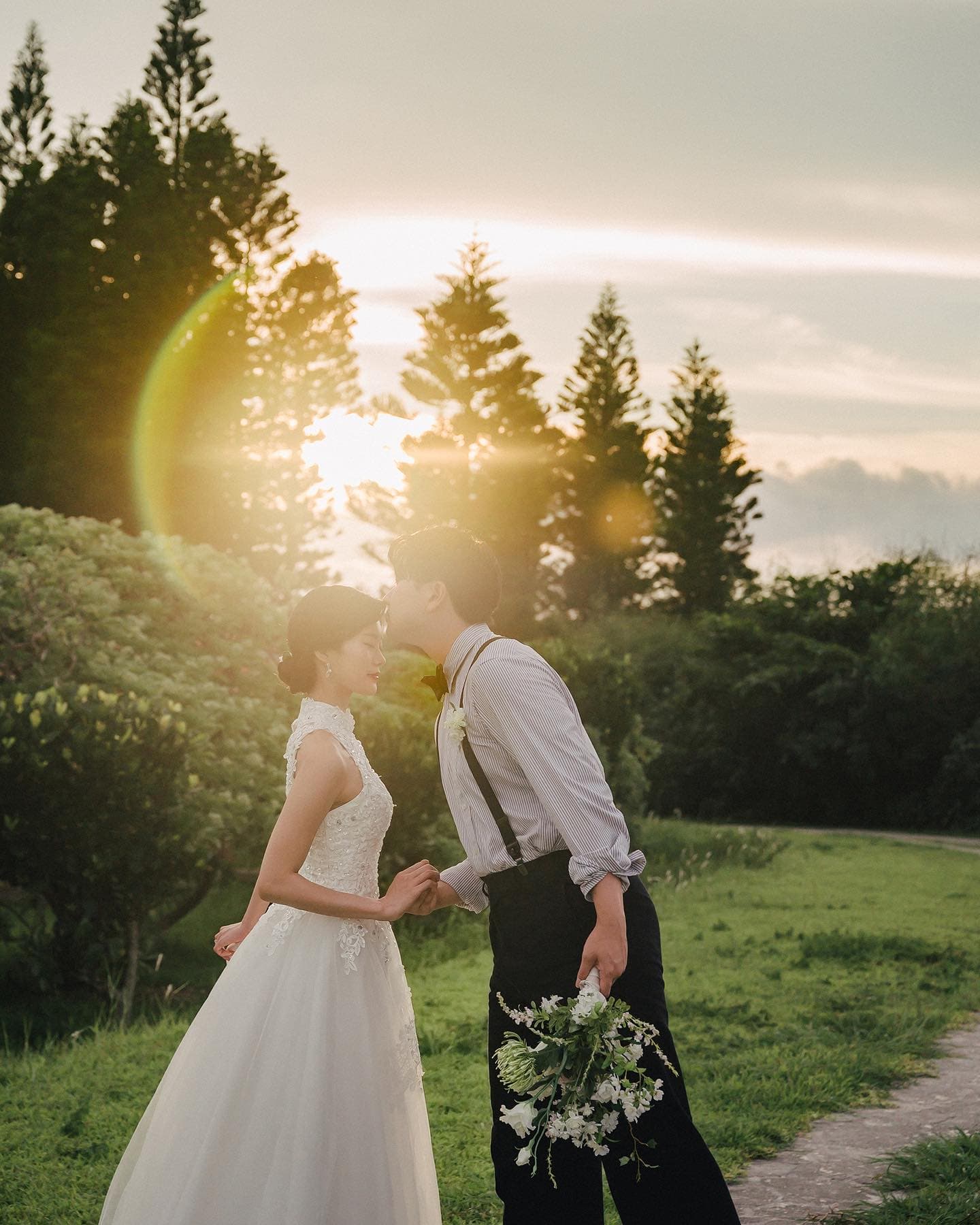 Groom kissing the bride forehead in golden evening light in Okinawa