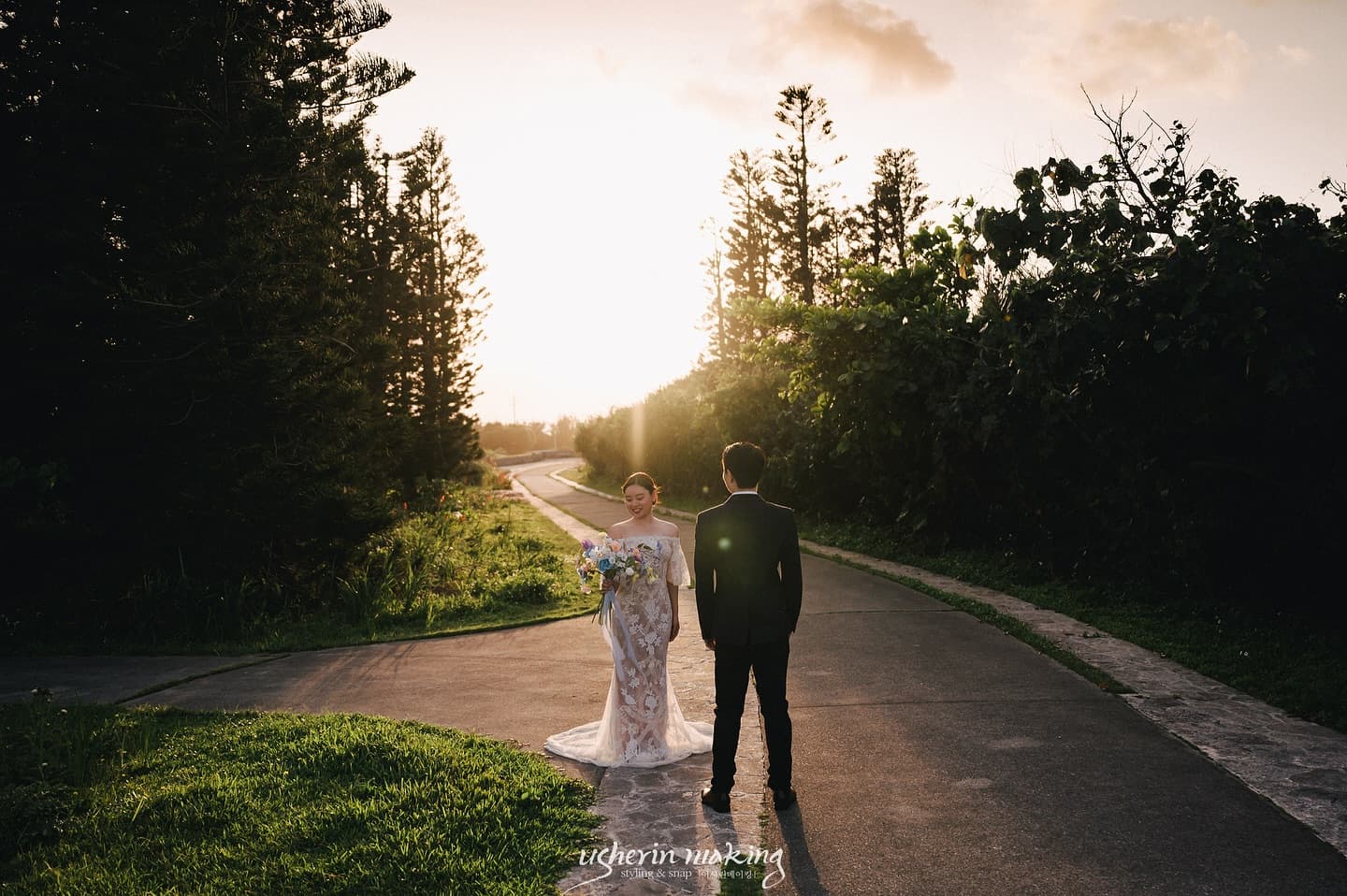 Couple facing each other on a tree-lined path bathed in golden sunset light in Okinawa