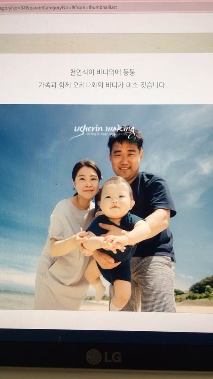 Family photo of parents holding up their baby on an Okinawa beach under a clear sky