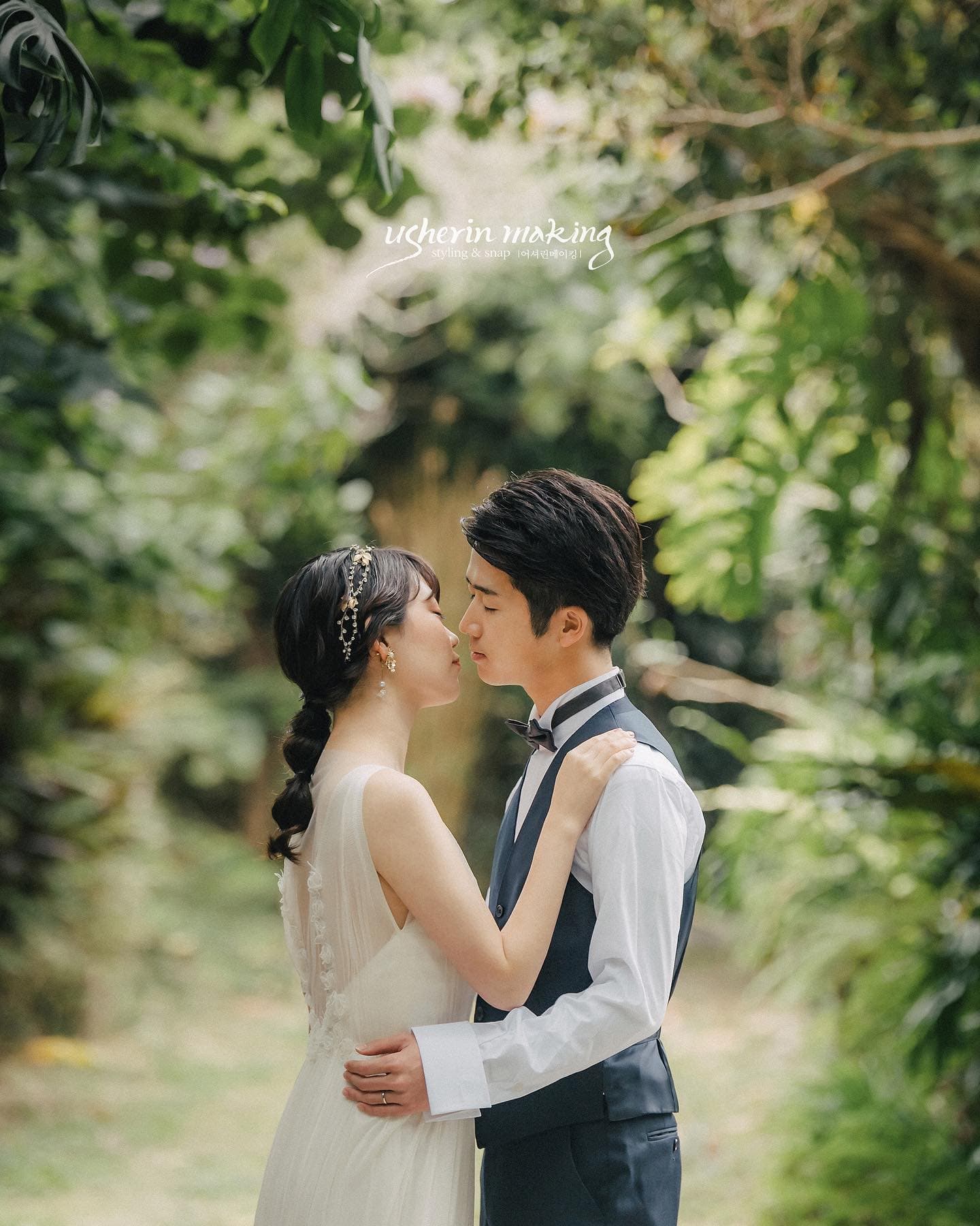 Couple kissing in dappled forest light, groom in a vest and bride in white, Okinawa