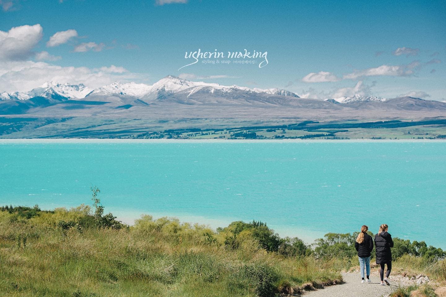 Couple walking toward a turquoise lake and snowy peaks in New Zealand