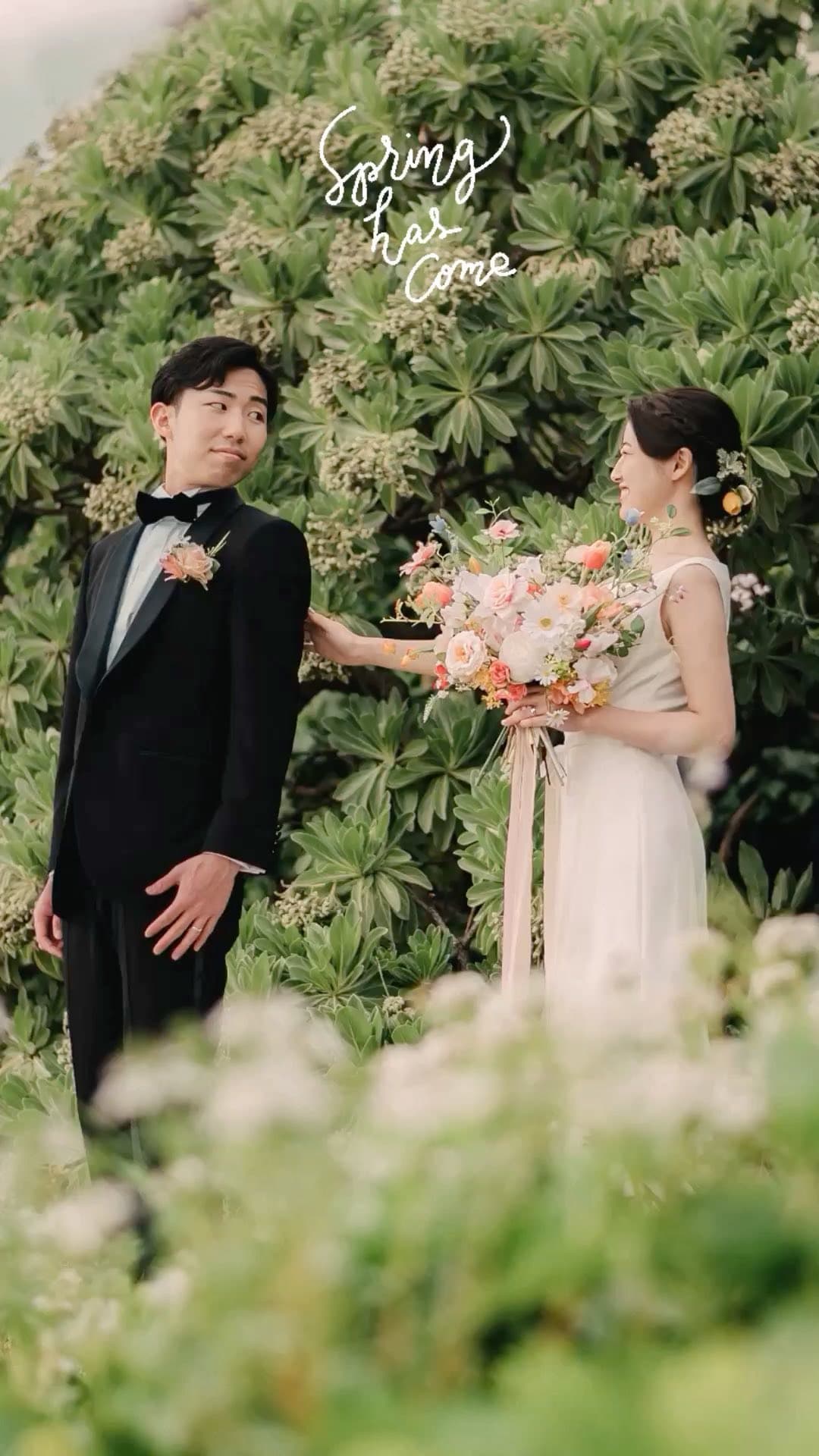 Bride with a bouquet and groom in a tuxedo against lush spring greenery in Okinawa