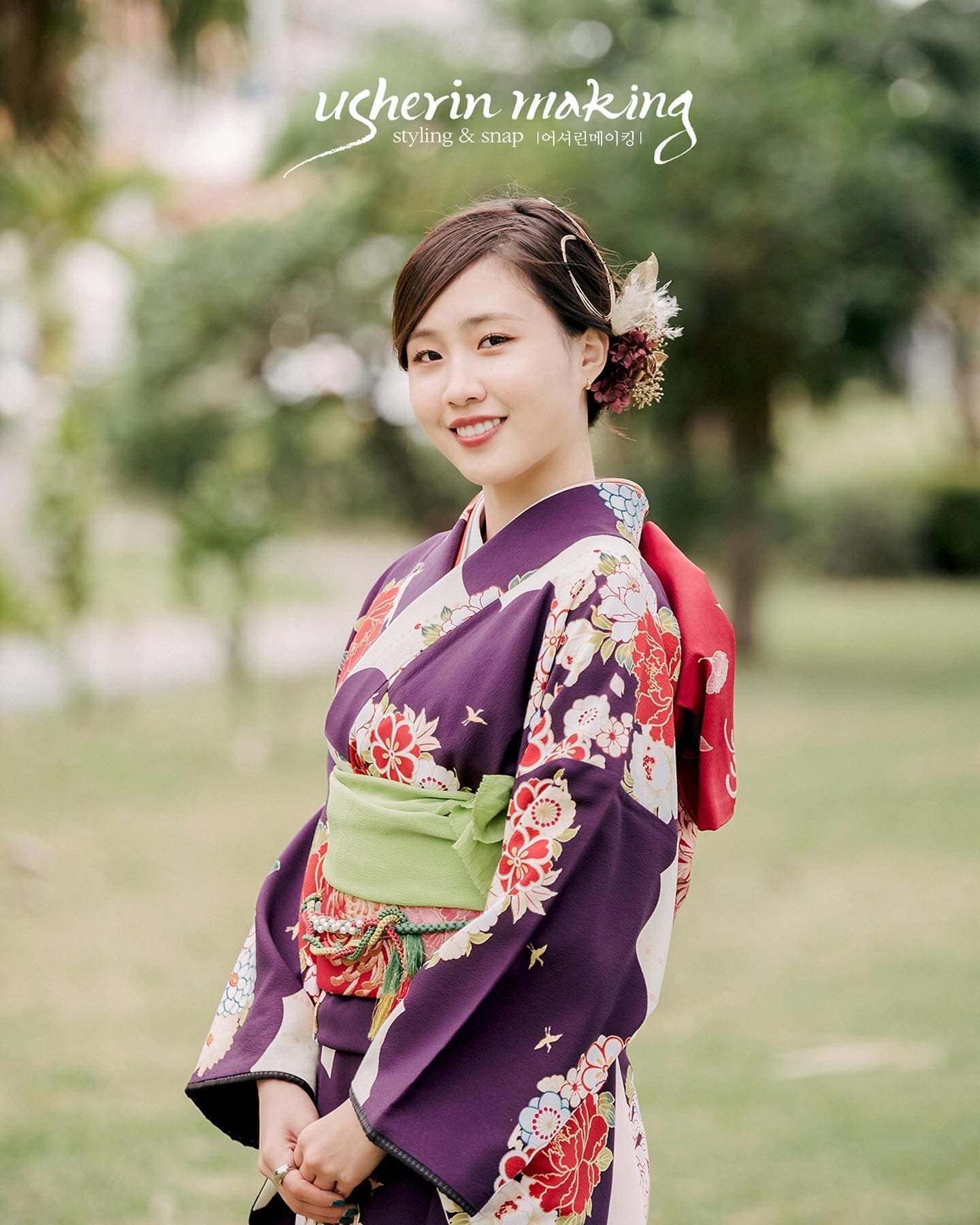 초록빛 공원에서 보라색 기모노를 입고 미소 짓는 여성
