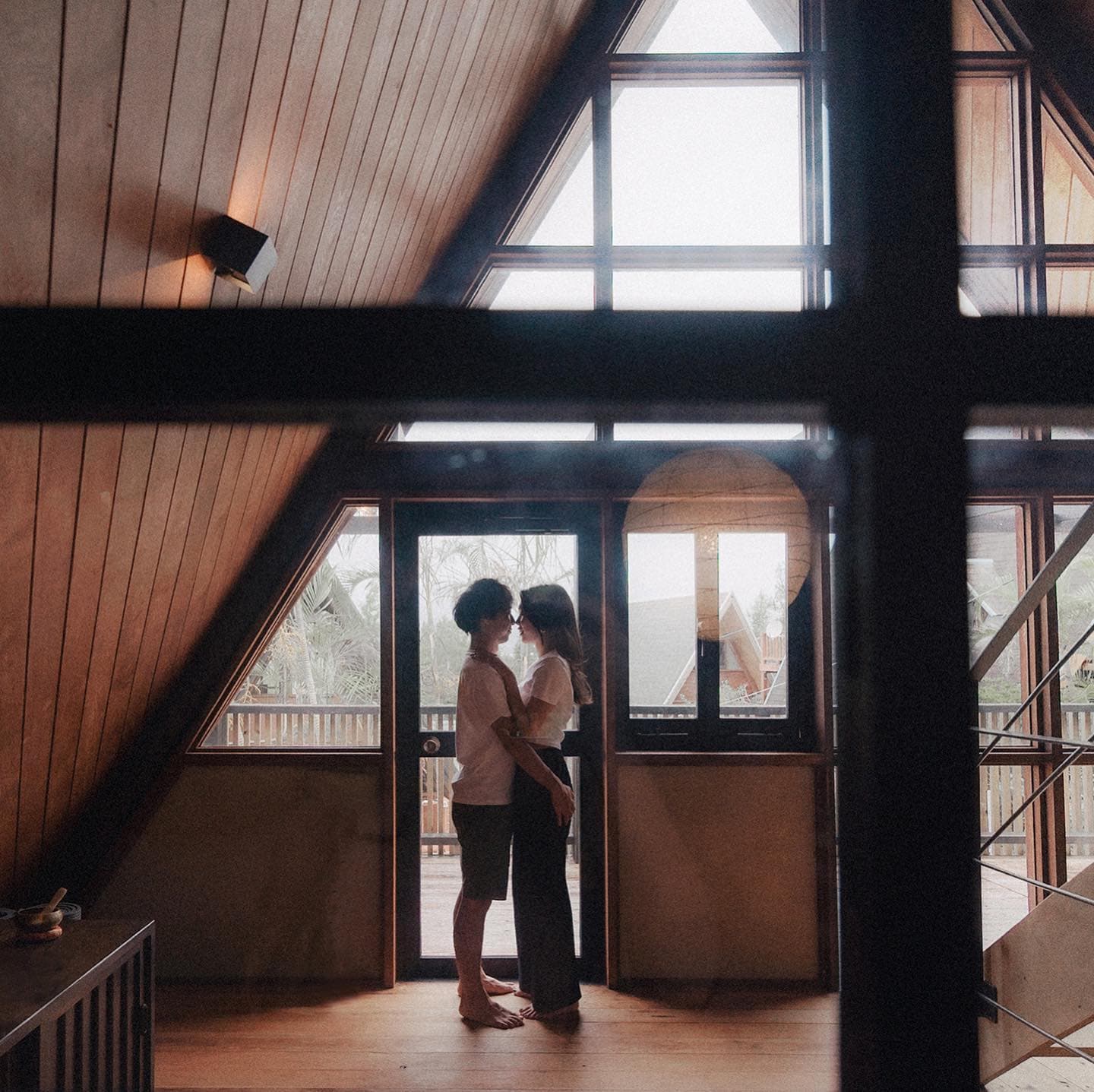 Couple touching foreheads by the doorway of an A-frame cabin