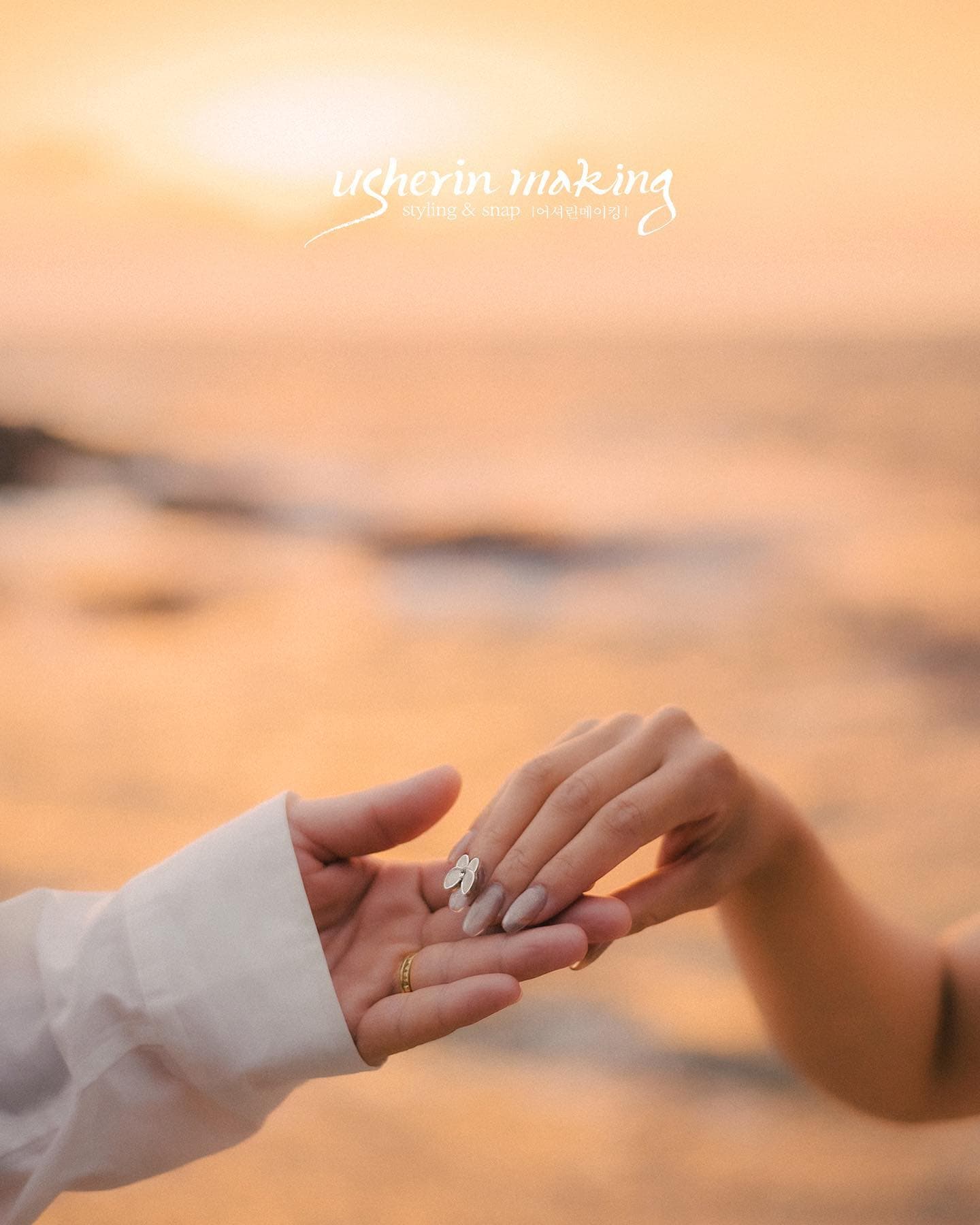 Close-up of the couple's hands with rings against a glowing sunset sea