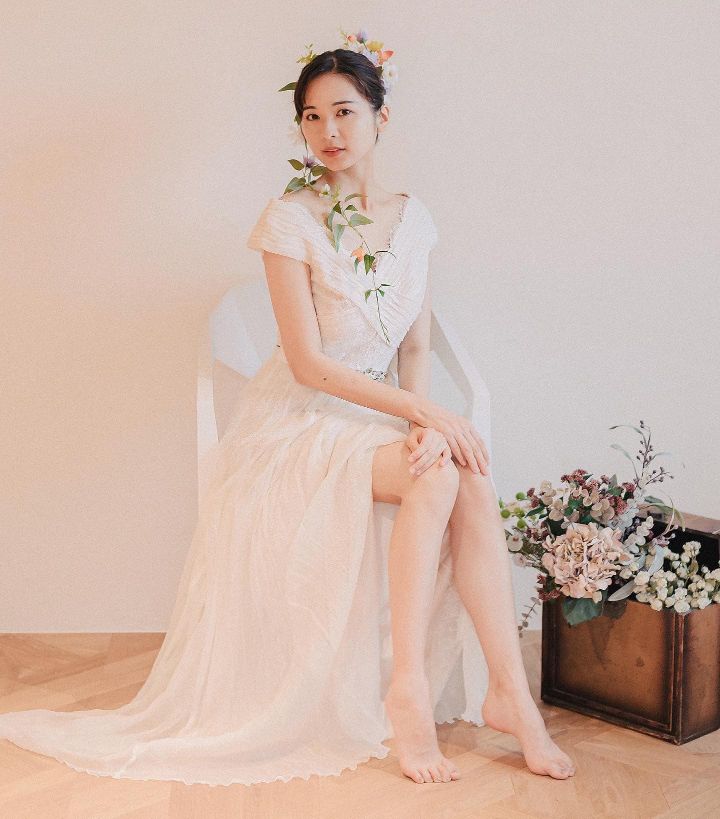 Studio portrait of a bride with a flower crown seated on a white chair