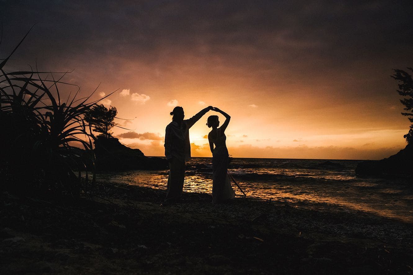 Silhouetted couple dancing on the shore against a fiery Okinawa sunset
