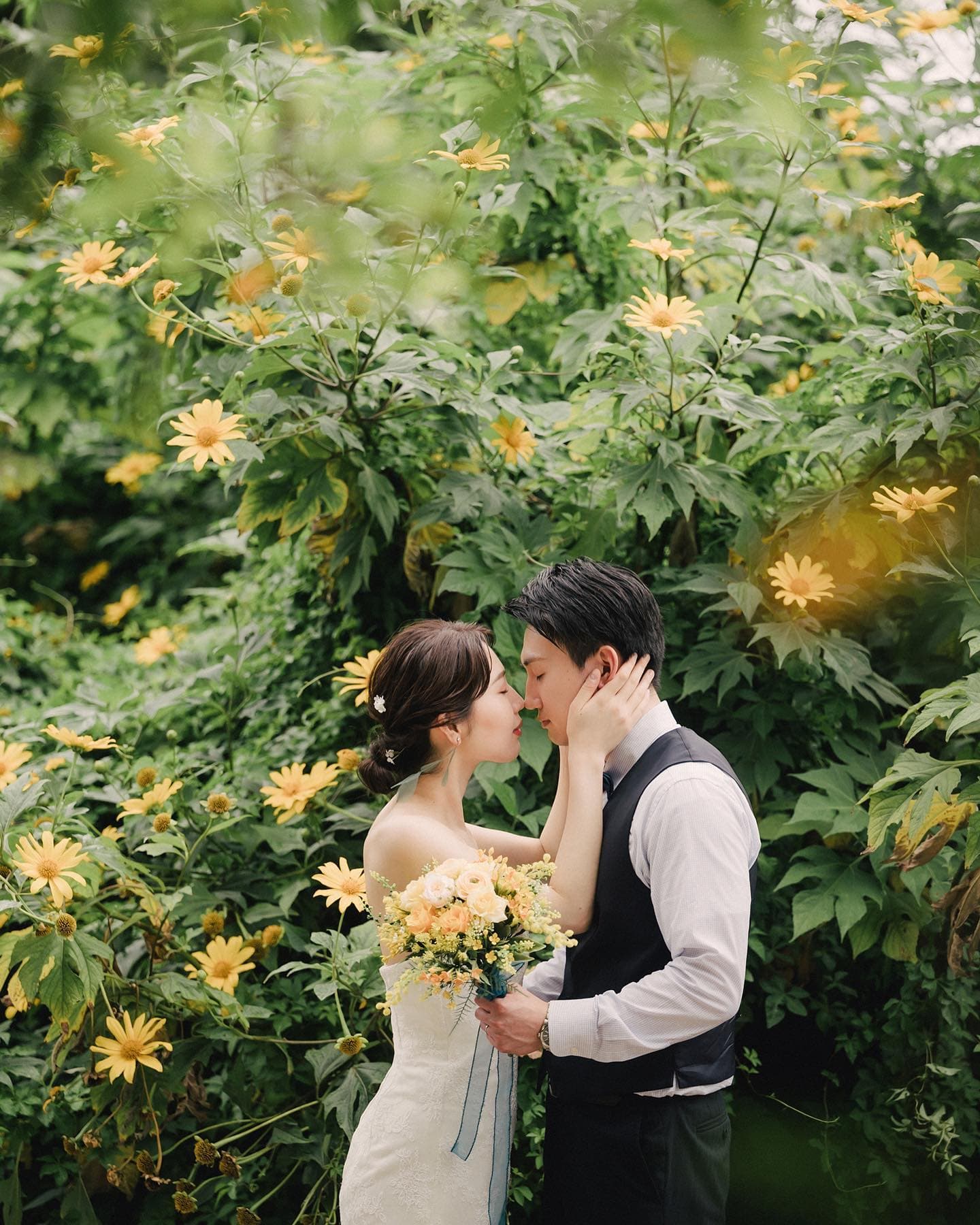 Bride and groom kissing among yellow wildflowers and lush greenery in Okinawa
