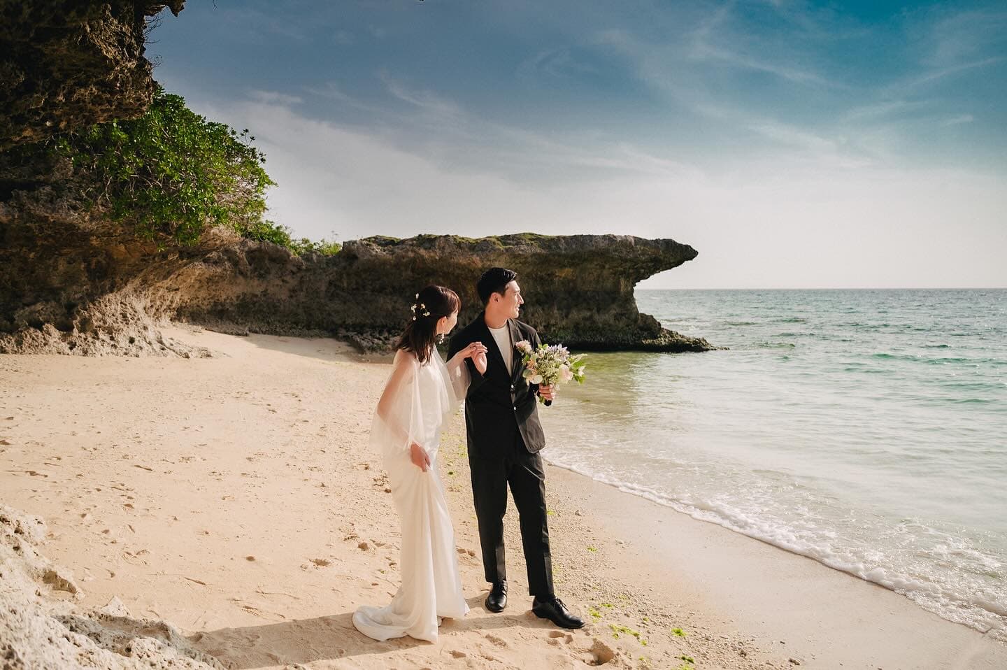 Couple walking toward the sea on an Okinawa beach, seen from behind