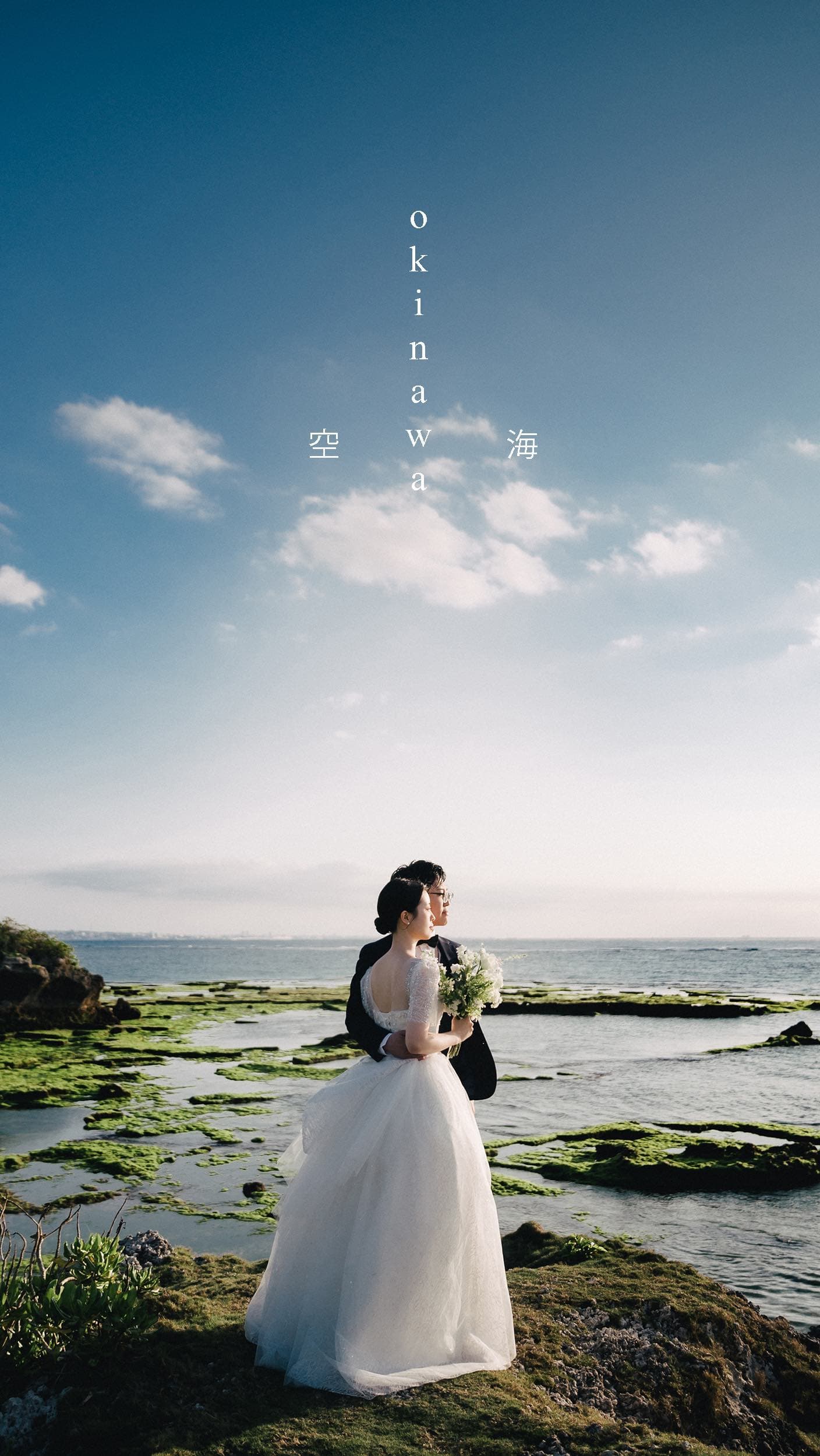 Bride and groom on mossy tidal rocks under a clear Okinawa sky