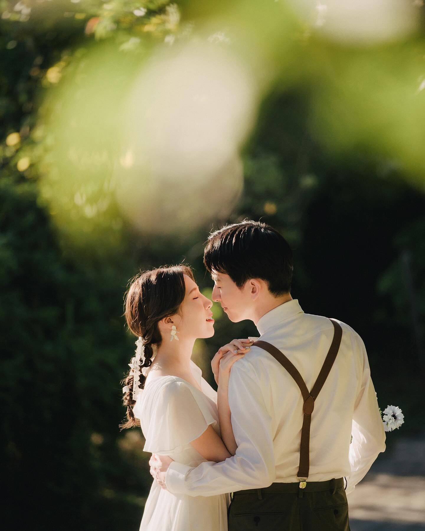Couple embracing forehead to forehead in dappled green light, Okinawa