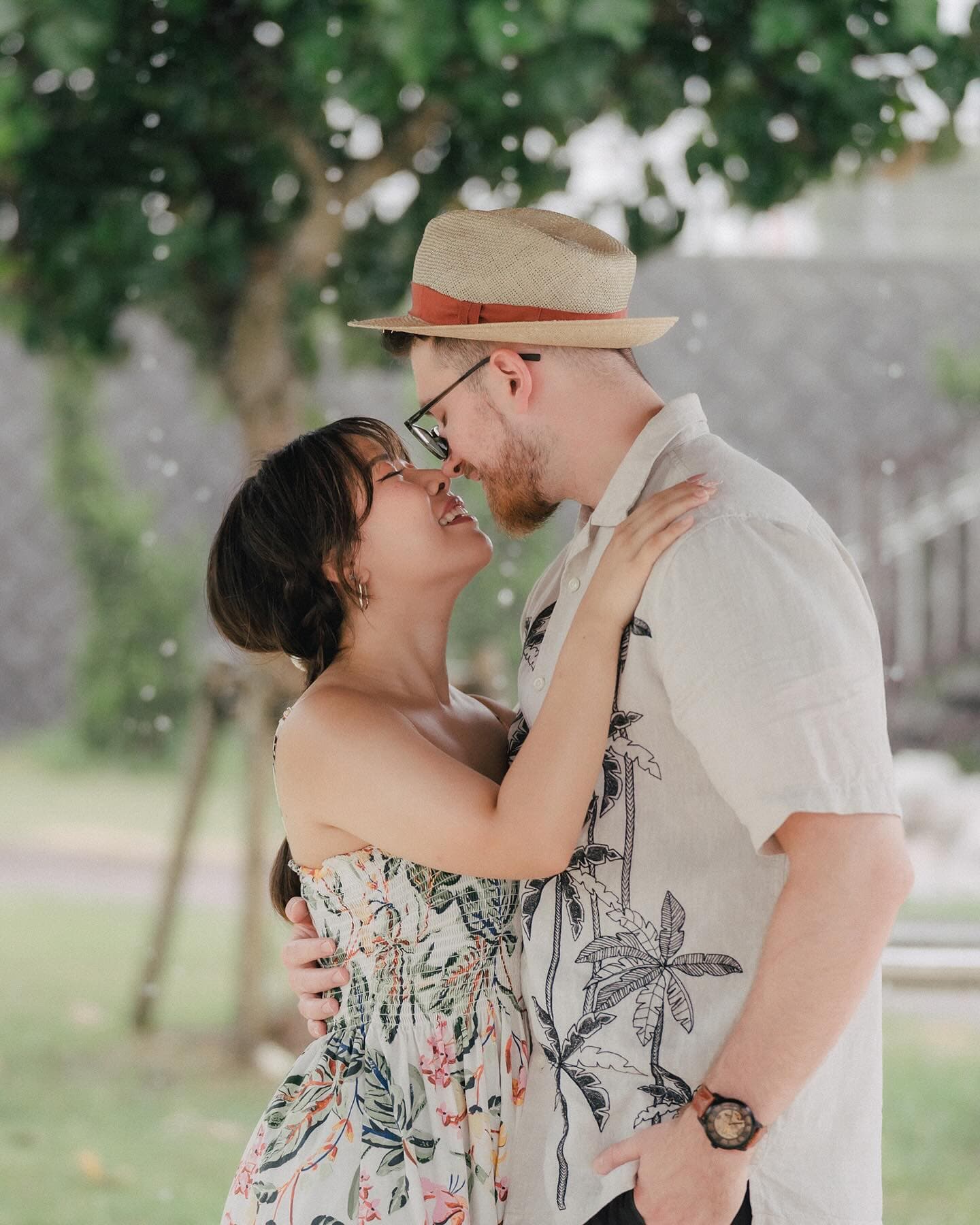 Couple kissing under a shady tree in Okinawa, dressed in aloha prints