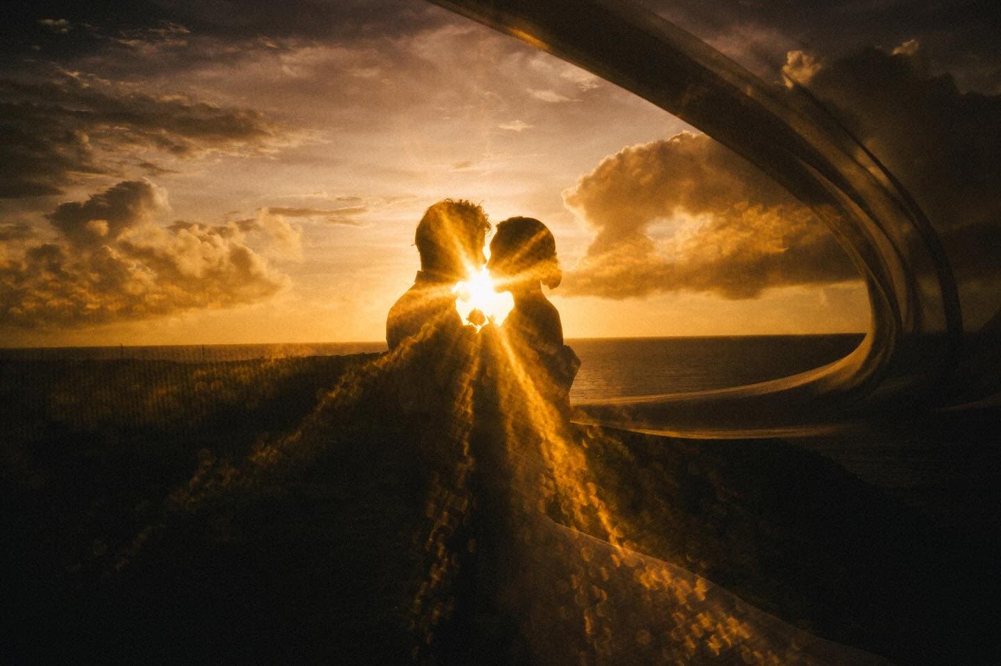 Couple framed by a golden sunburst at sunset on the Okinawa coast