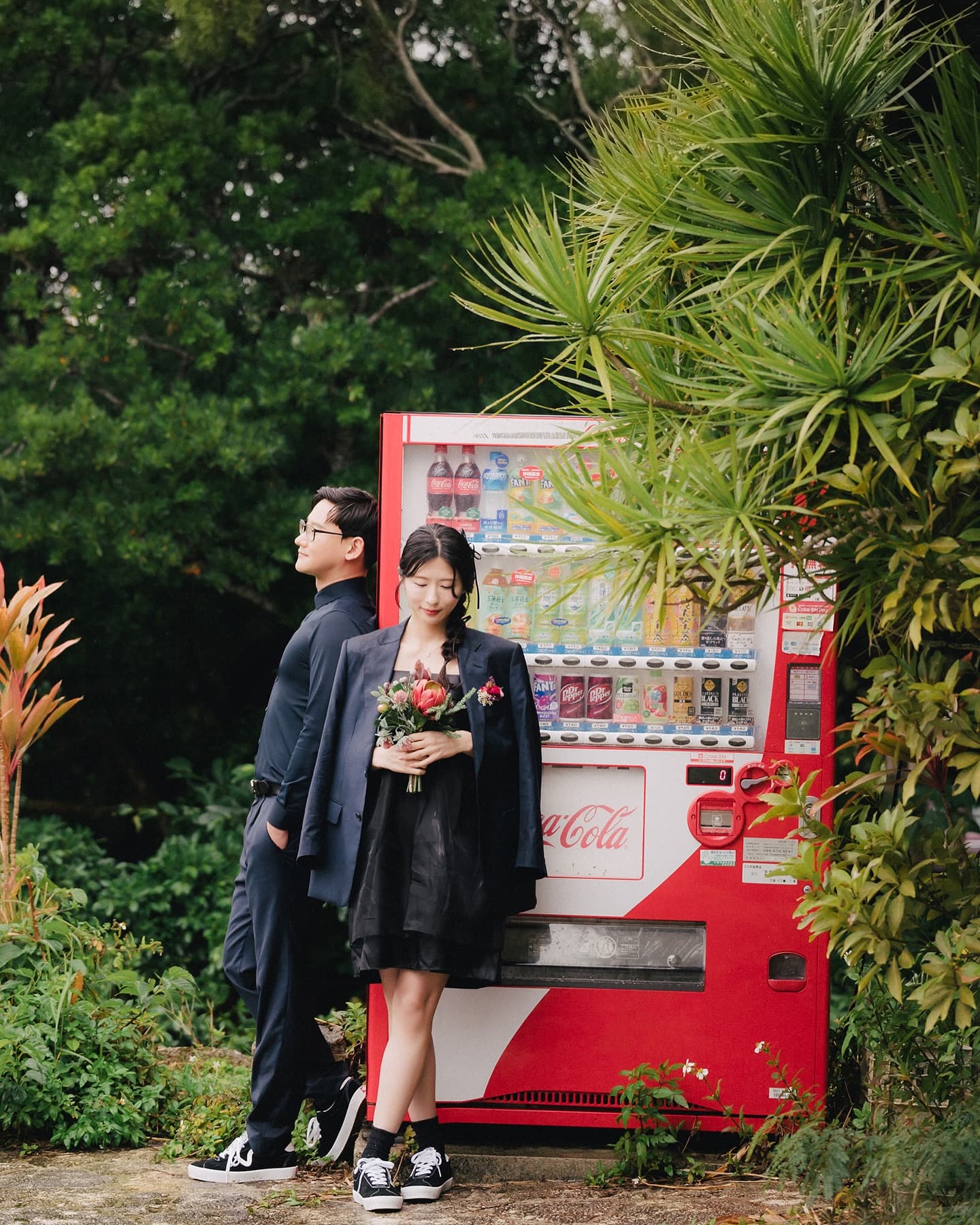 Couple posing by a red vending machine and palm tree in Okinawa