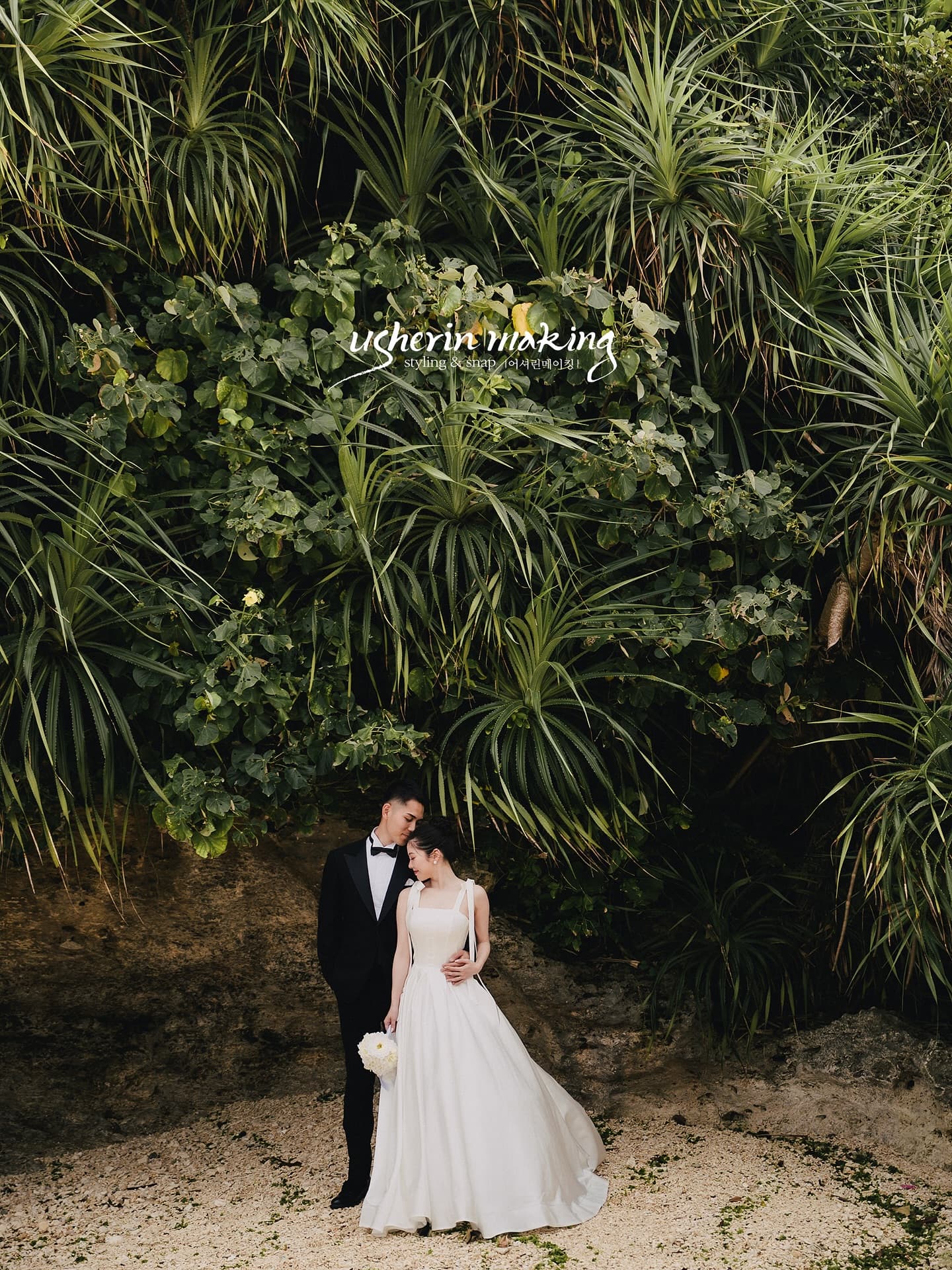 Couple nestled beneath lush tropical greenery on an Okinawa beach