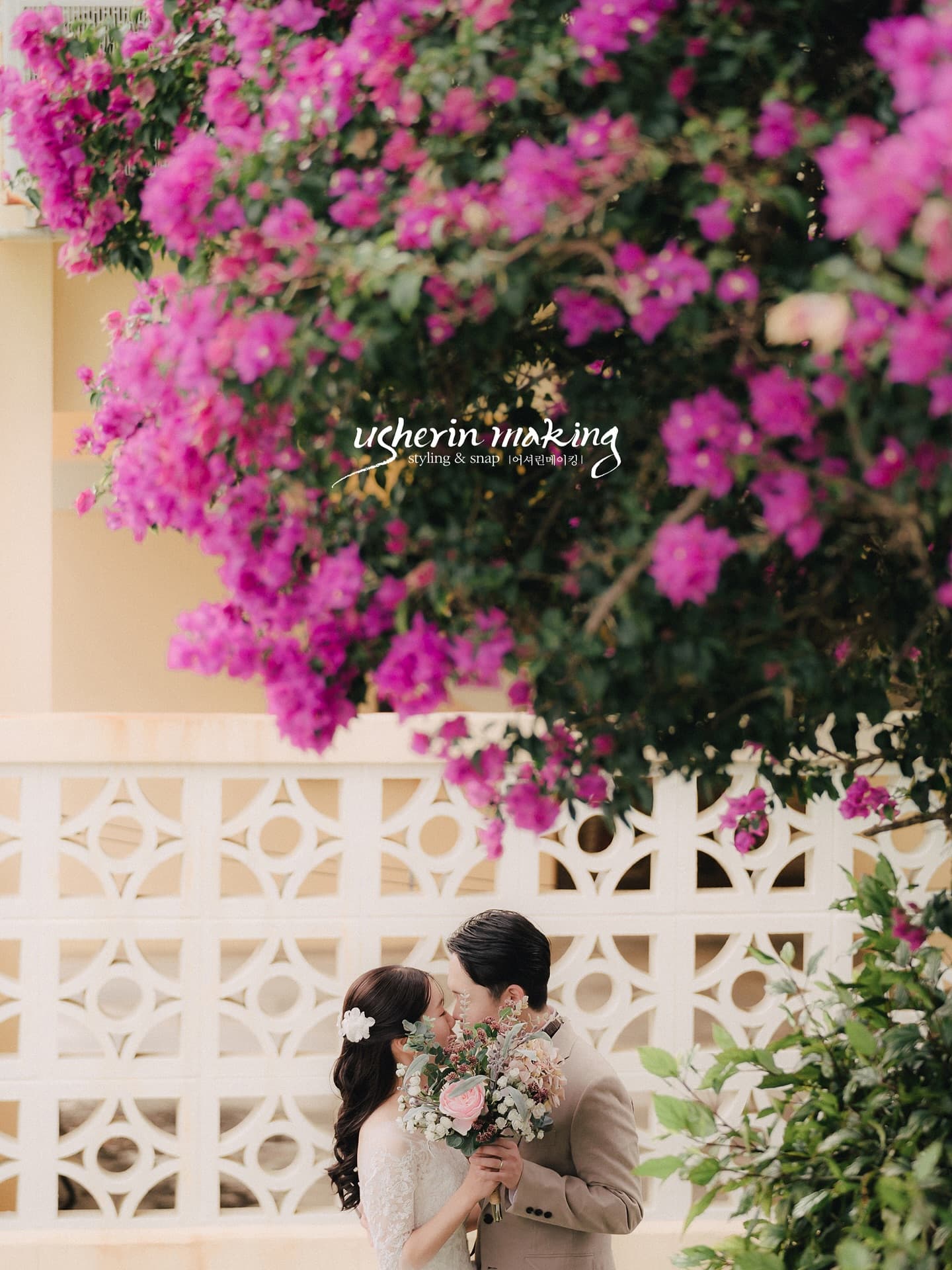 Bride and groom kissing beneath vivid pink blossoms in Okinawa