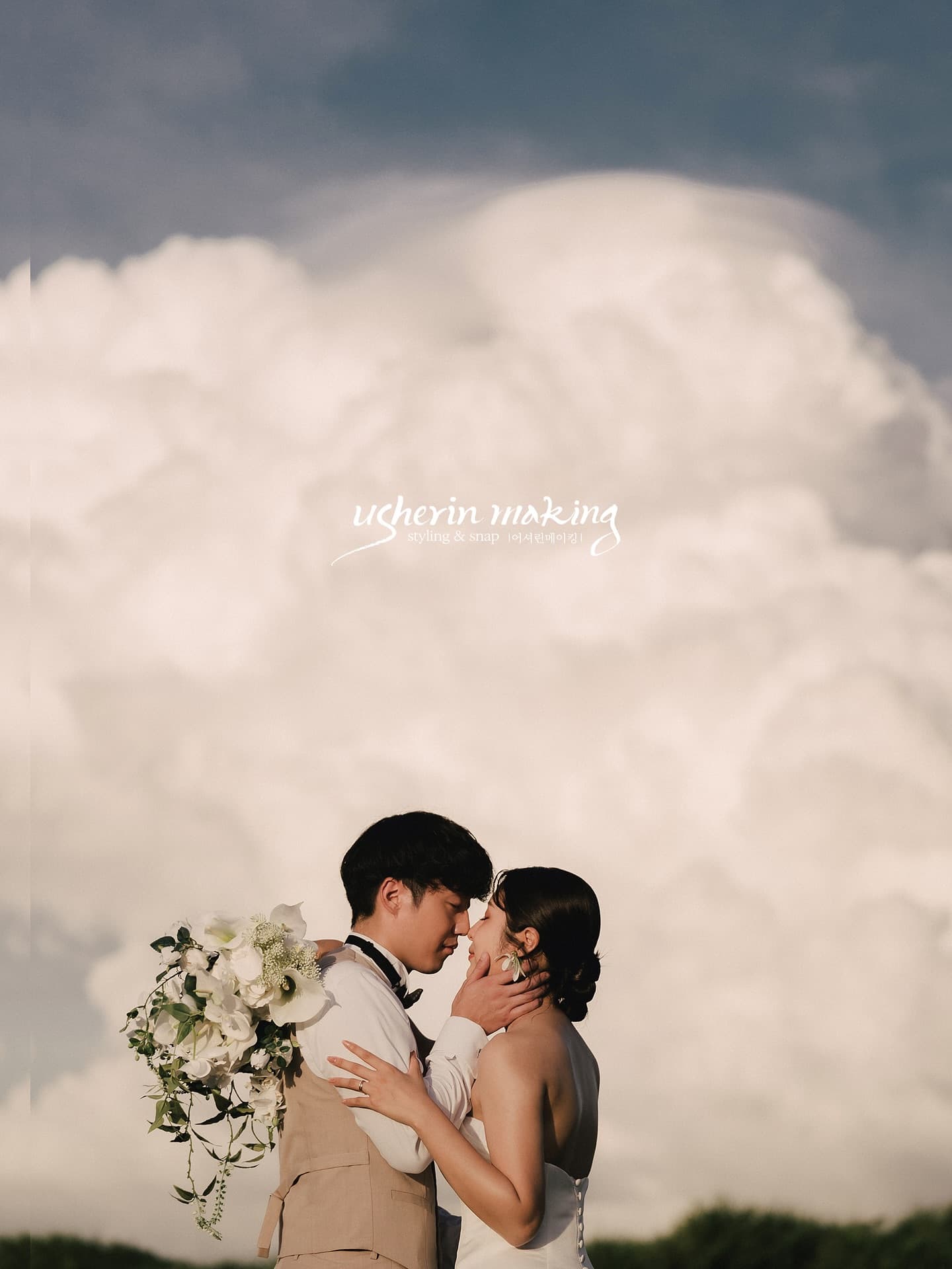 Couple kissing before towering summer clouds in Okinawa, groom holding a white bouquet