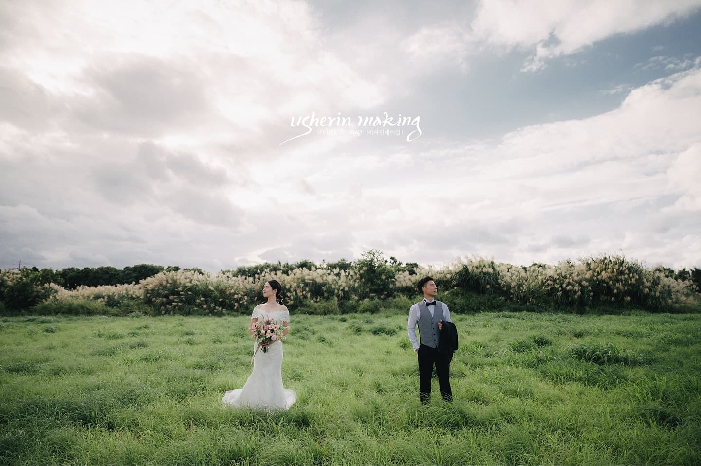 Bride and groom standing in a field of silver grass under a moody autumn sky in Okinawa