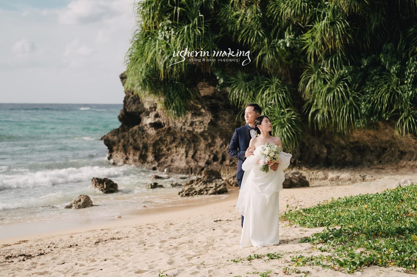Bride and groom on a sunny Okinawa beach with waves and greenery