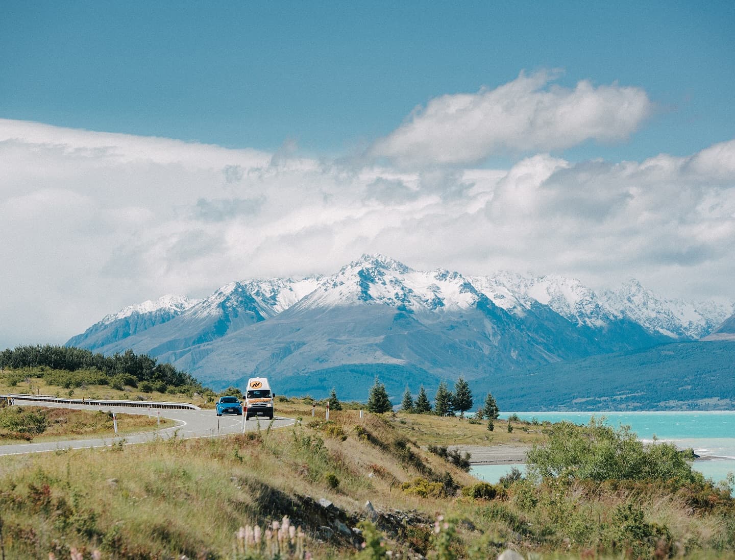 Snow-capped mountains and a turquoise glacial lake along a scenic road in New Zealand