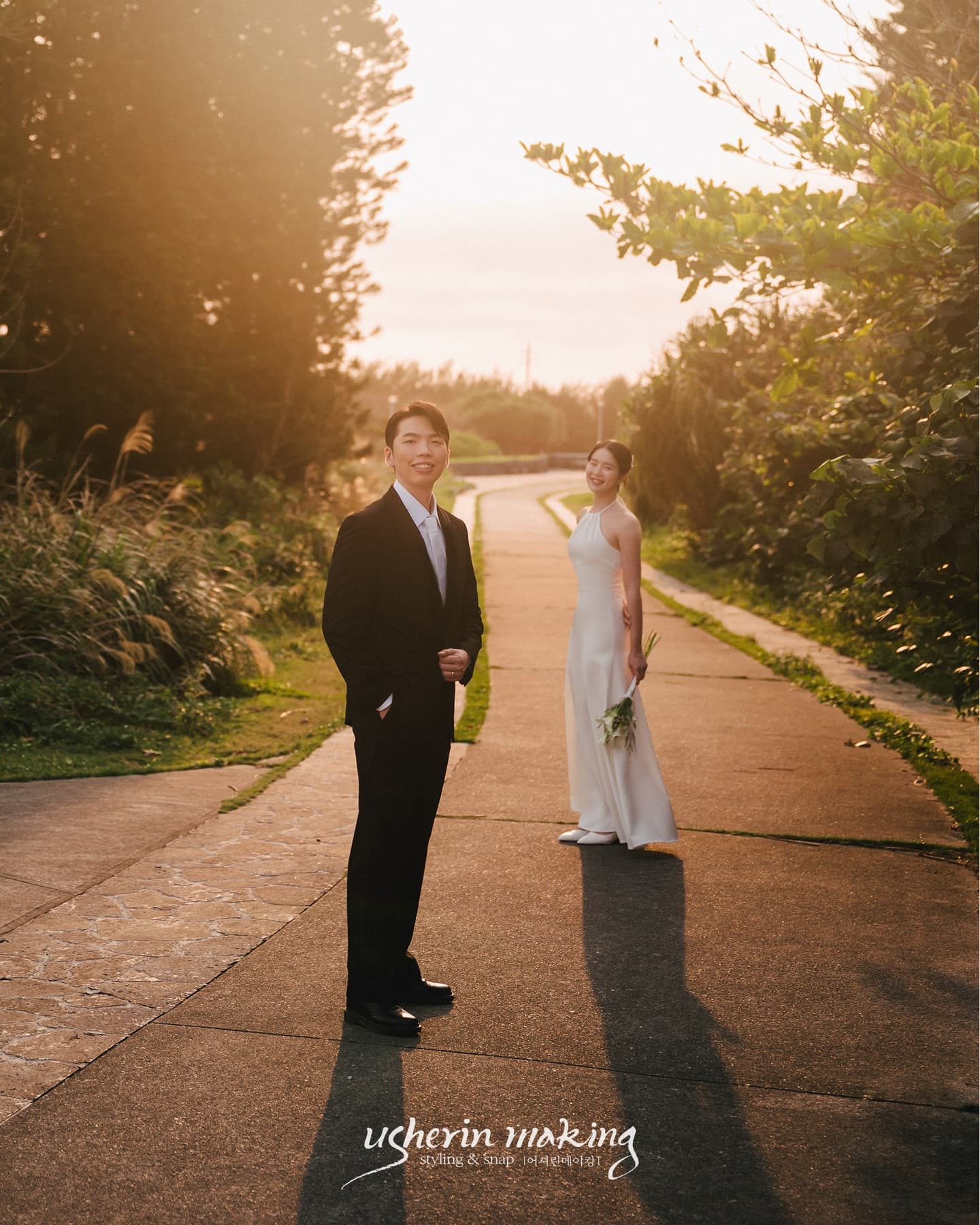 Bride and groom on a tree-lined path glowing in the Okinawa sunset