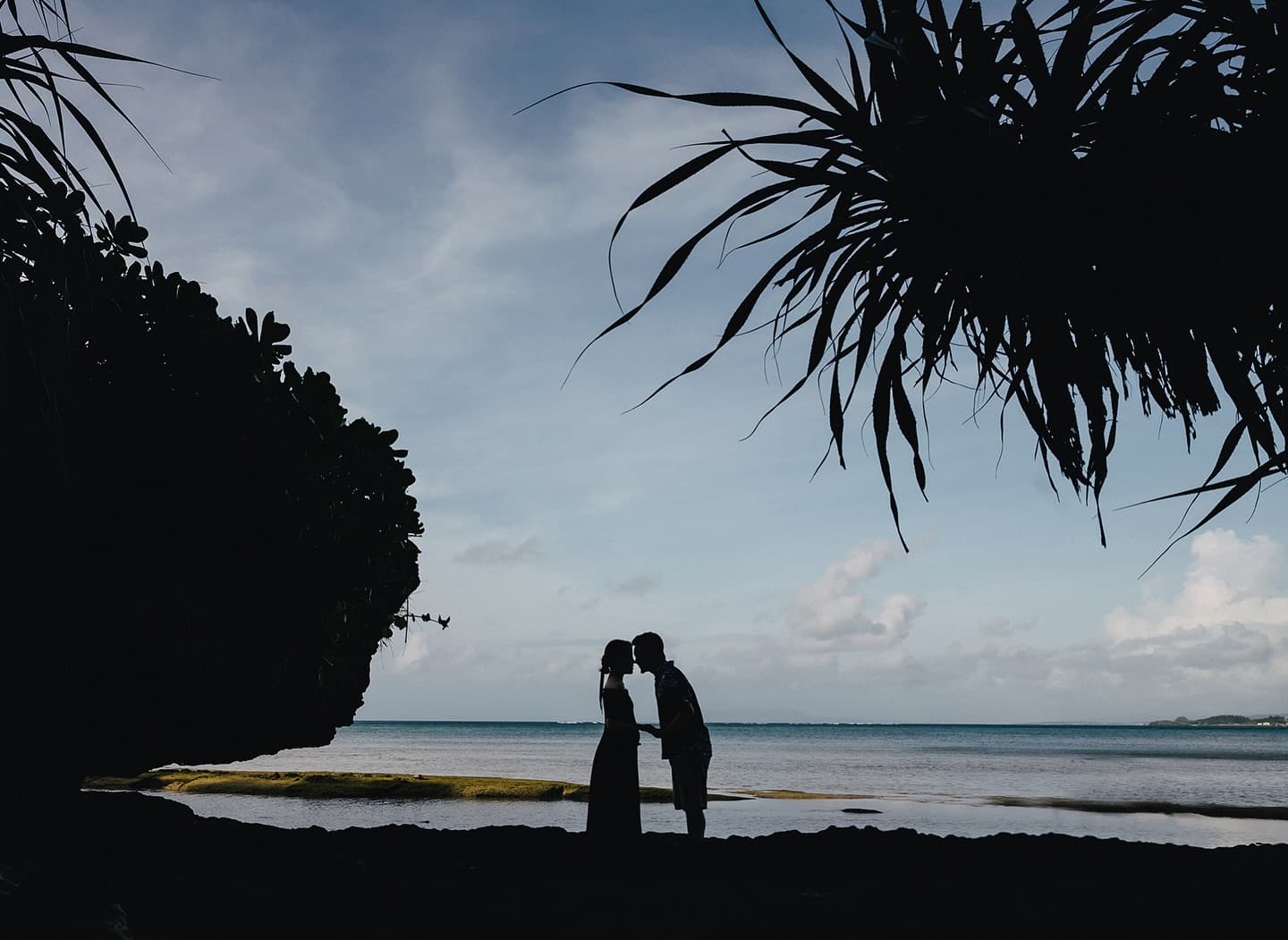 Expecting couple share a kiss in silhouette by the Okinawa sea